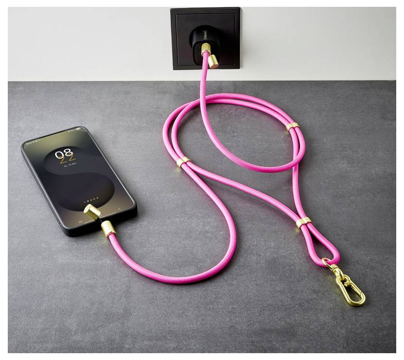 Ein Smartphone lädt auf einem Tisch mit einem rosa Ladekabel, das in eine Wandsteckdose eingesteckt ist.
