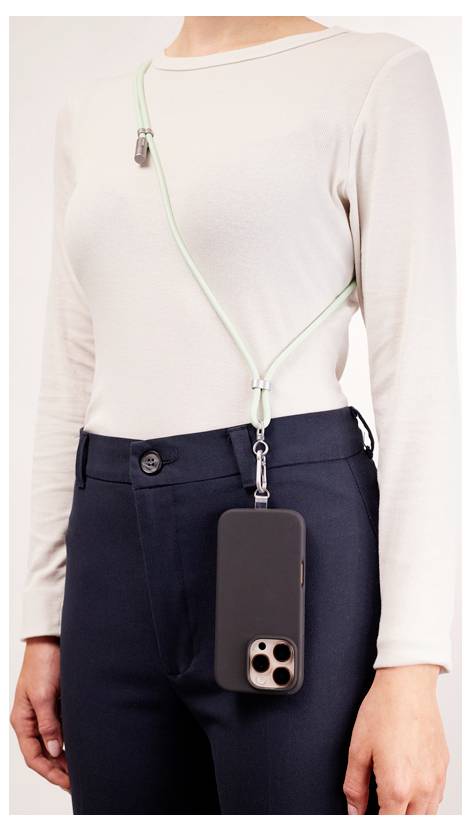 Eine Person mit einem neutral gefärbten Oberteil und dunkler Hose, die ein Smartphone präsentiert, das an einem Umhängeriemen für bequemes, freihändiges Tragen befestigt ist.