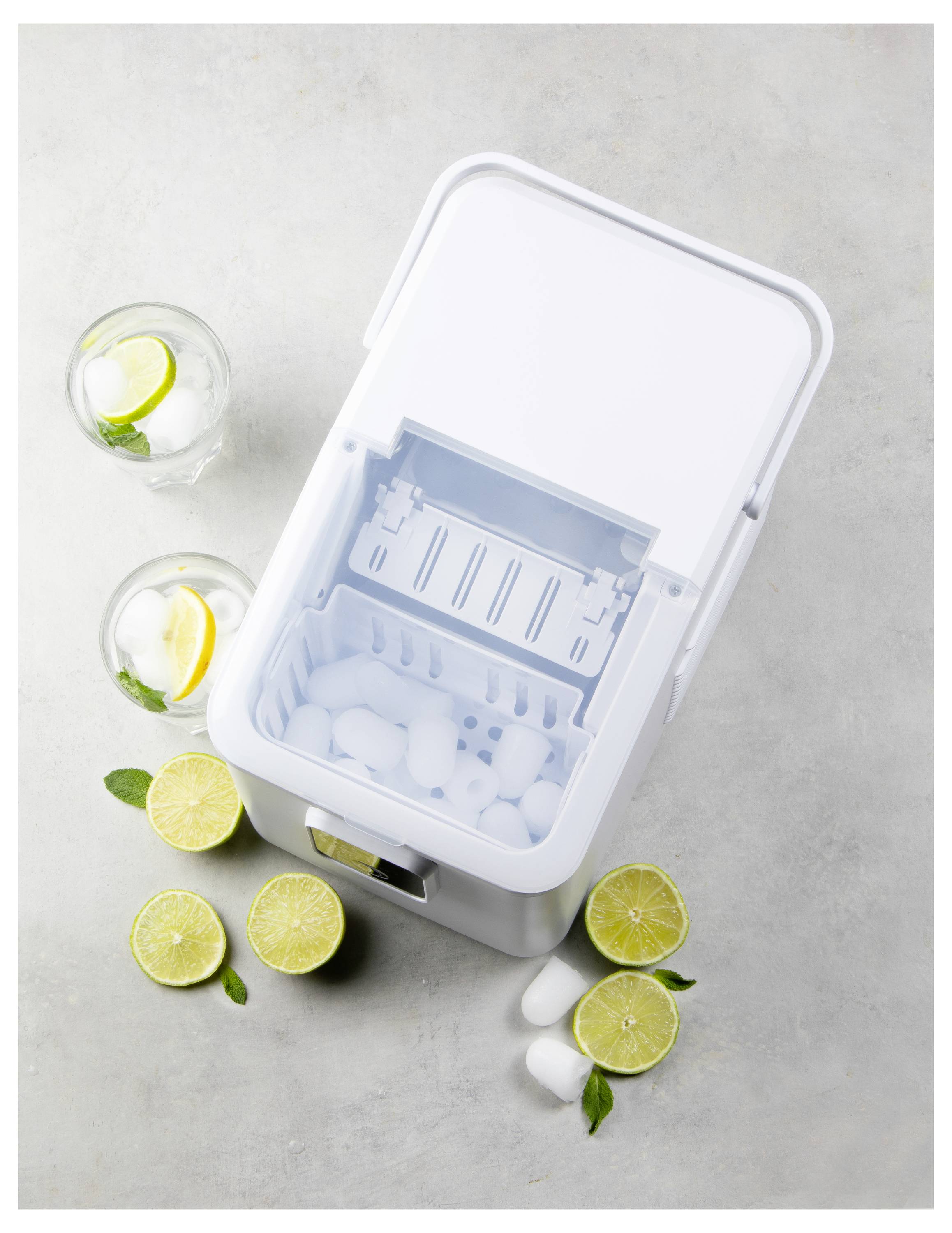 Ein weißer Eiswürfelbereiter, von oben zu sehen, ist mit Eiswürfeln gefüllt. Zwei Gläser mit Eis, Zitronenscheiben und Minze befinden sich neben aufgeschnittenen Zitronen.