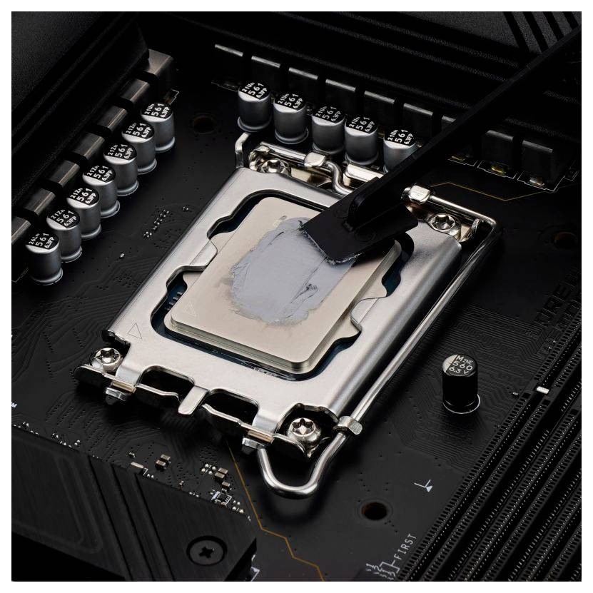 Eine Nahaufnahme eines Prozessorsockels auf einem Motherboard, wobei thermische Paste auf den Prozessor zum Zwecke der Kühlung aufgetragen wird.