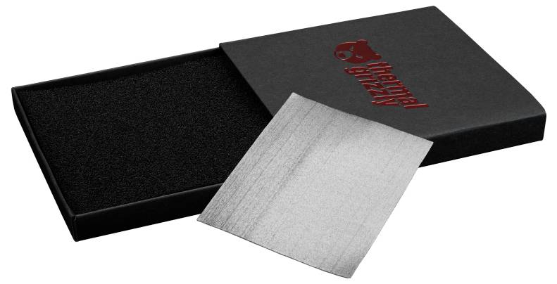 Eine schwarze Verpackung der Marke 'Thermal Grizzly' mit einem teilweise herausgezogenen Graphit-Wärmeleitpad, was auf ein Produkt zur thermischen Verwaltung hinweist.