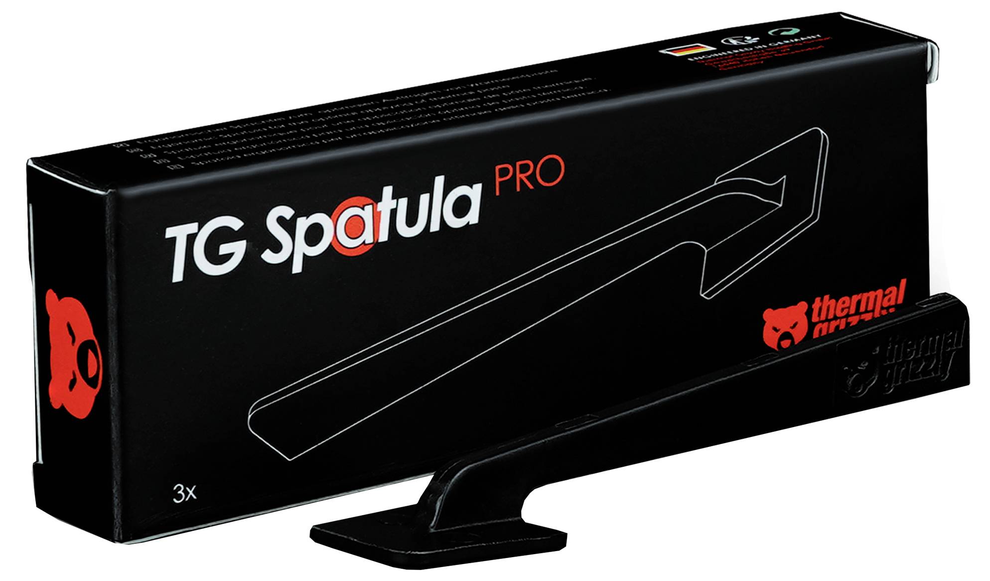 Ein schwarzer TG Spatula Pro Werkzeug mit einer Schachtel, die sein Bild, Markenlogo und Merkmale zeigt. Die Verpackung weist darauf hin, dass es für die Auftragung von Wärmeleitpaste entwickelt wurde.