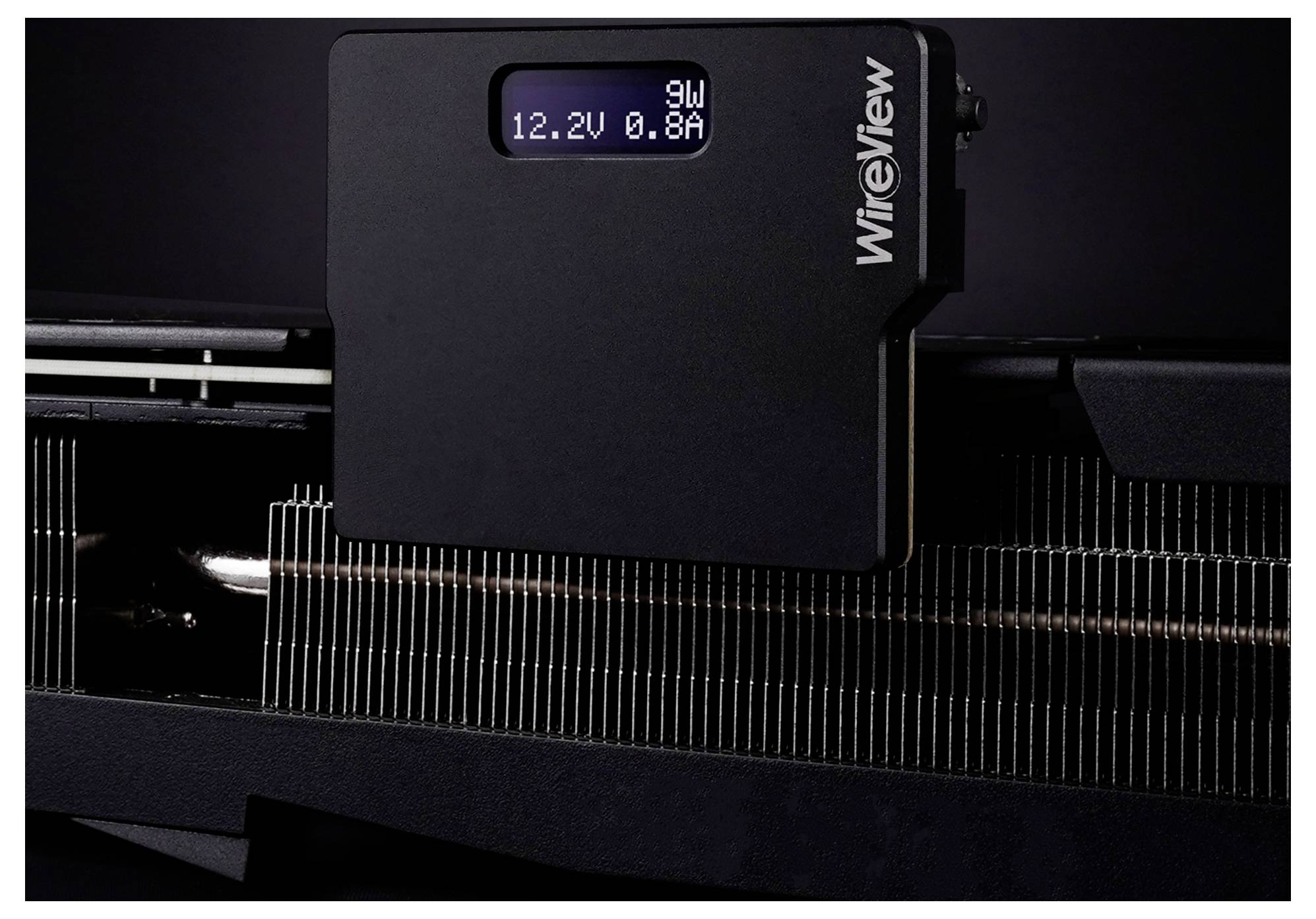 Ein schwarzer digitaler Wattmeter mit einem Display, das auf dunklem Hintergrund ‚9W 12,2V 0,8A' anzeigt und wahrscheinlich den Stromverbrauch eines Geräts misst.
