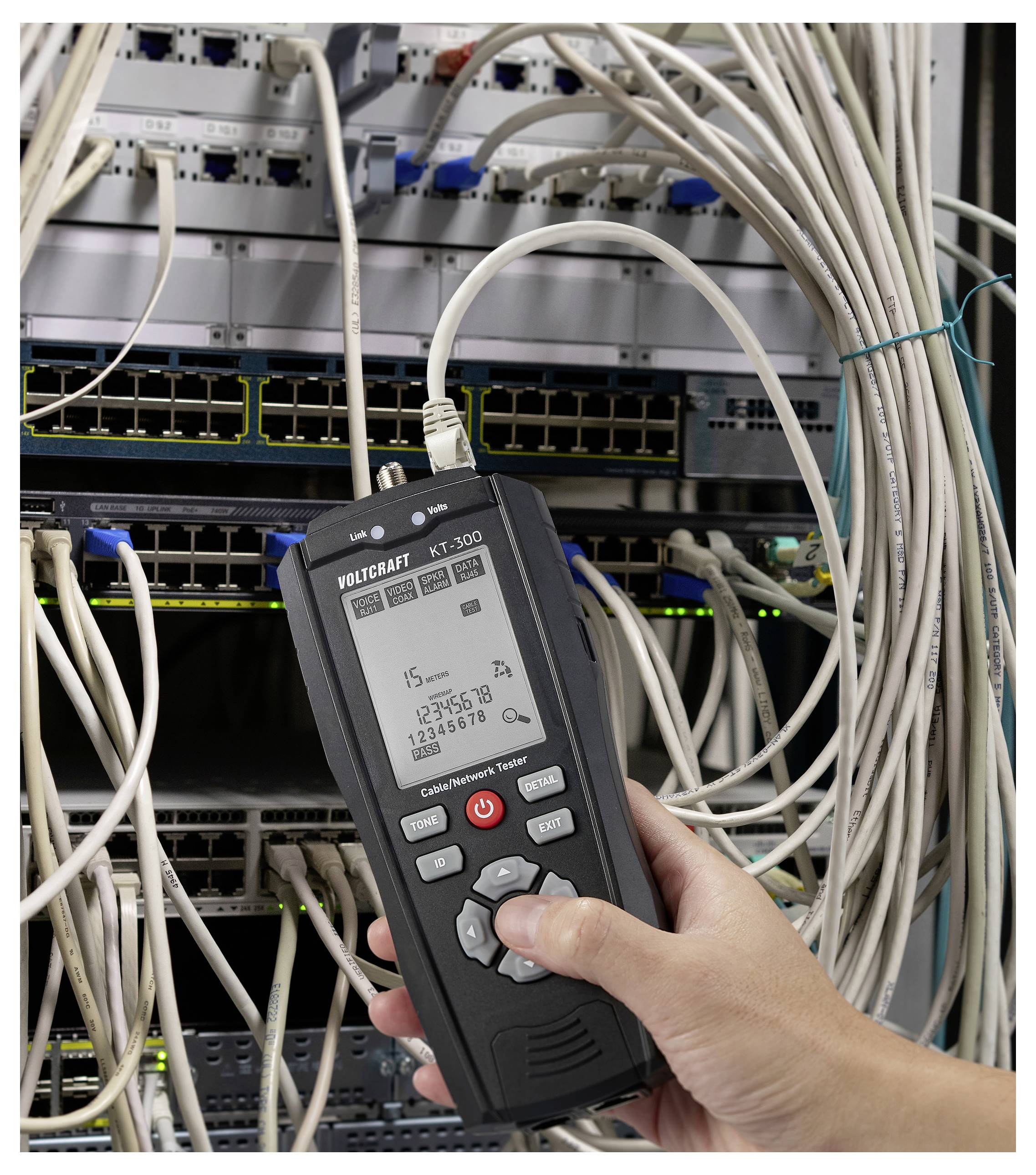 Eine Person hält ein Netzwerkkabel-Testgerät neben einem Serverrack und überprüft die Konnektivität. Der Bildschirm zeigt netzwerkbezogene Daten und Zahlen an.