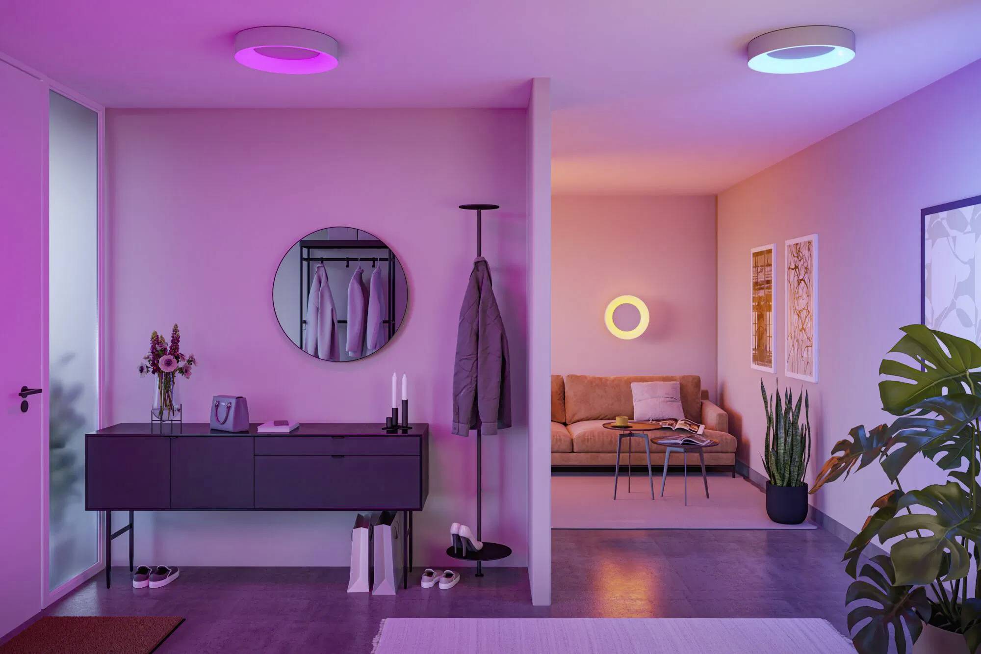 Ein moderner Wohnraum mit violetter und rosa Ambientebeleuchtung. Ausgestattet mit einem Sofa, Couchtisch, Garderobenständer, Pflanzen und Wandkunst.