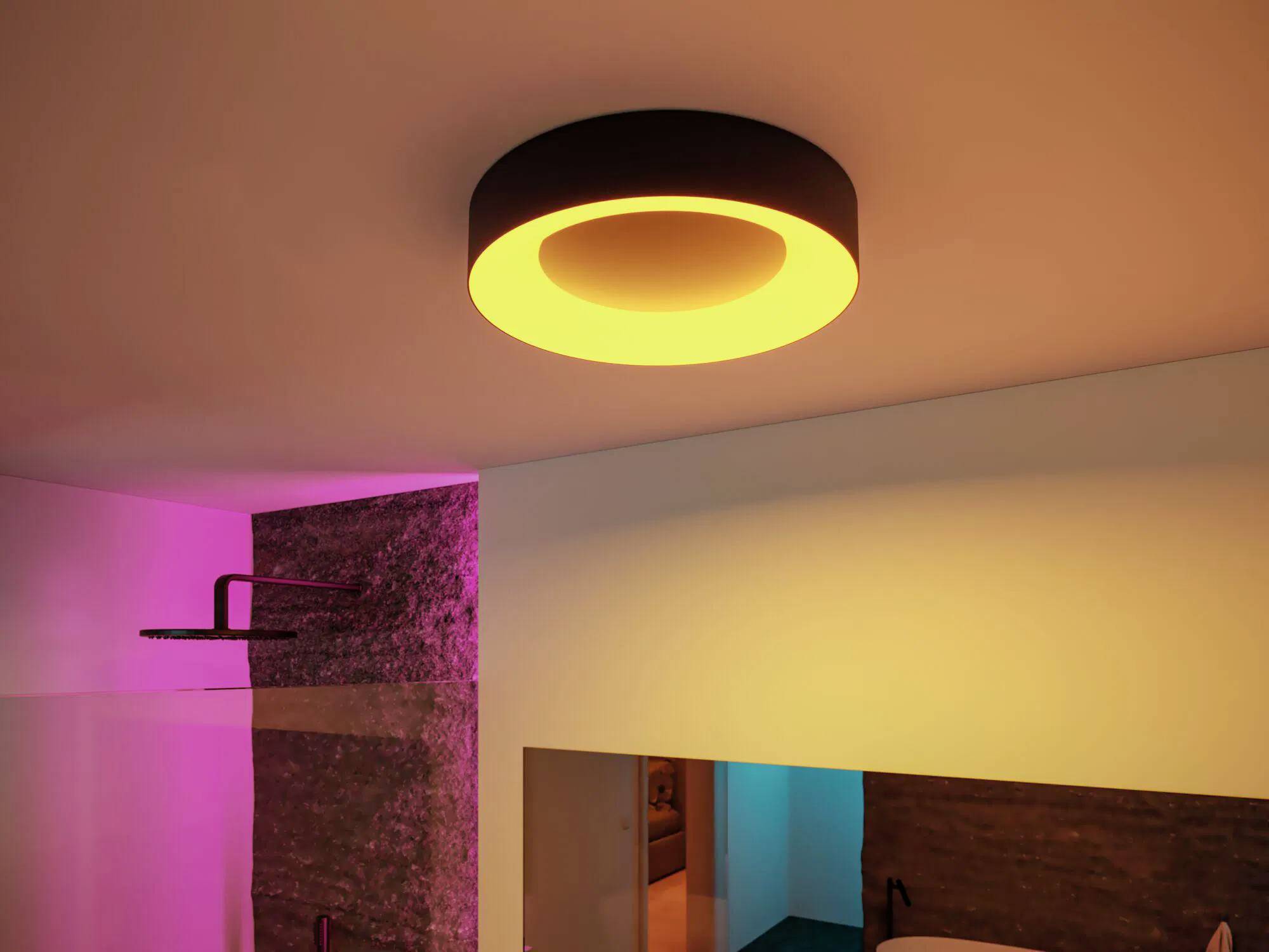 Eine moderne Deckenleuchte mit warmem Glanz erhellt einen Raum mit rosa und blauen Akzenten an Stein- und weißen Wänden und schafft eine gemütliche Atmosphäre.