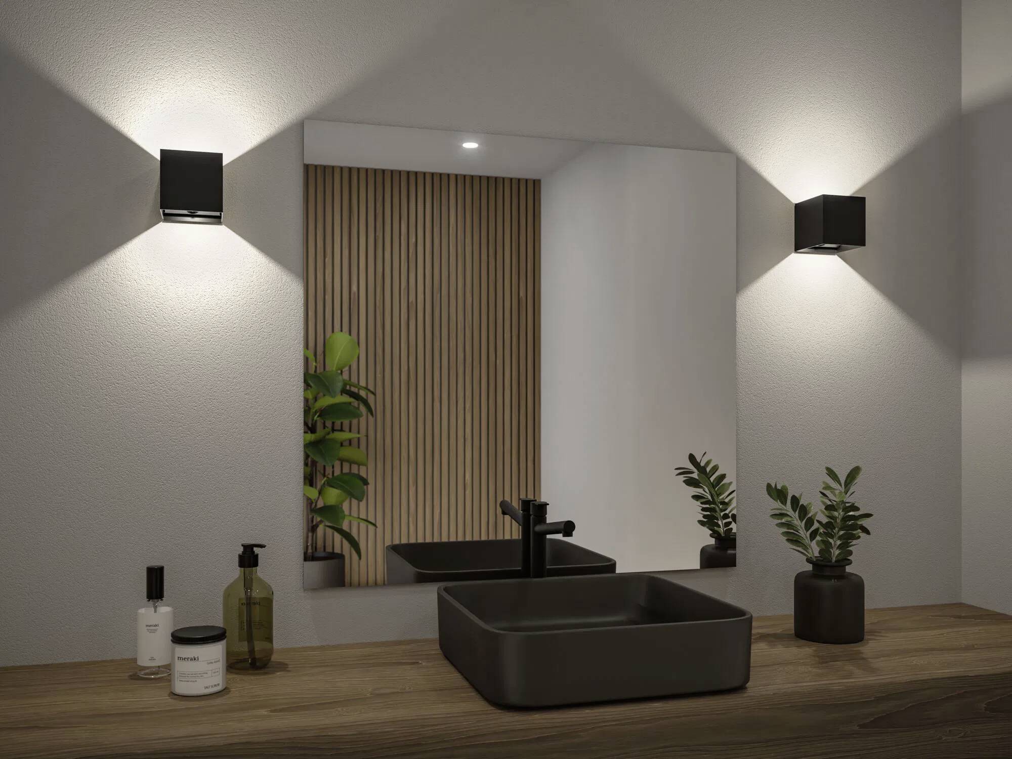 Eine moderne Badezimmerarmatur zeigt ein quadratisches schwarzes Waschbecken, Wasserhahn und kleine Pflanzen auf einer Holztheke, unter rechteckigen Wandleuchten.
