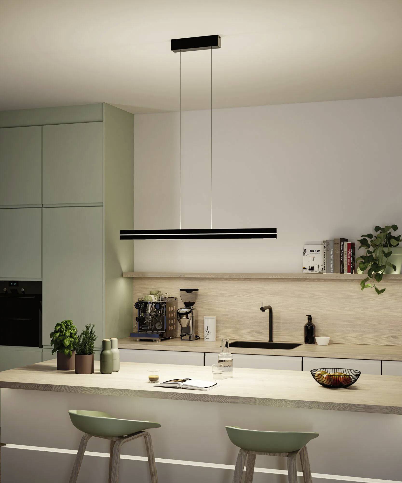 Moderne Küche mit einer hängenden Lampe über einer Kücheninsel, ausgestattet mit Barhockern, Pflanzen und einer Kaffeemaschine auf einer hellholzfarbenen Arbeitsplatte.