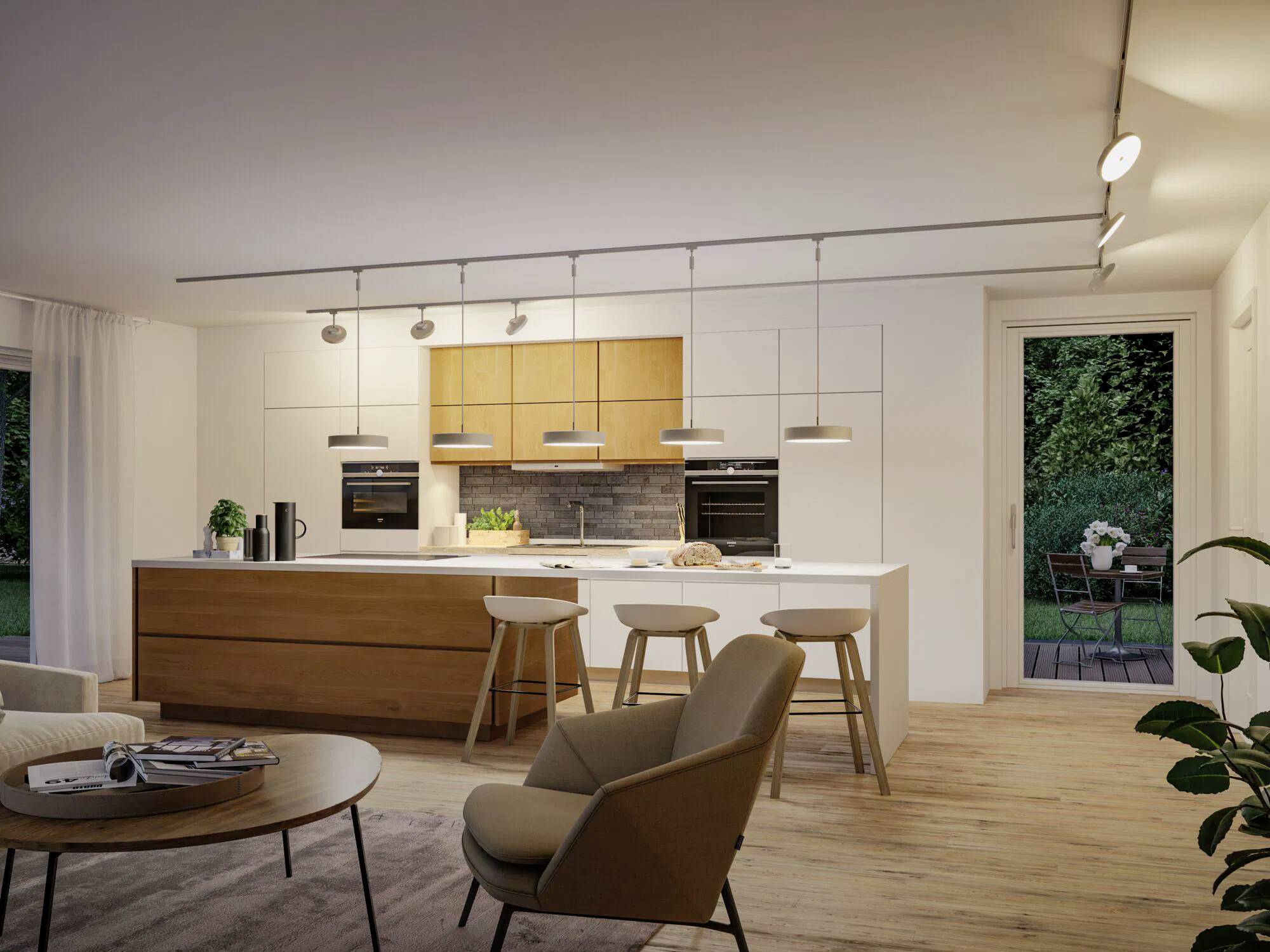 Eine moderne Küche und ein Wohnbereich mit Holzschränken, einer zentralen Insel mit Barhockern und einem Blick in den Garten durch eine Glastür.
