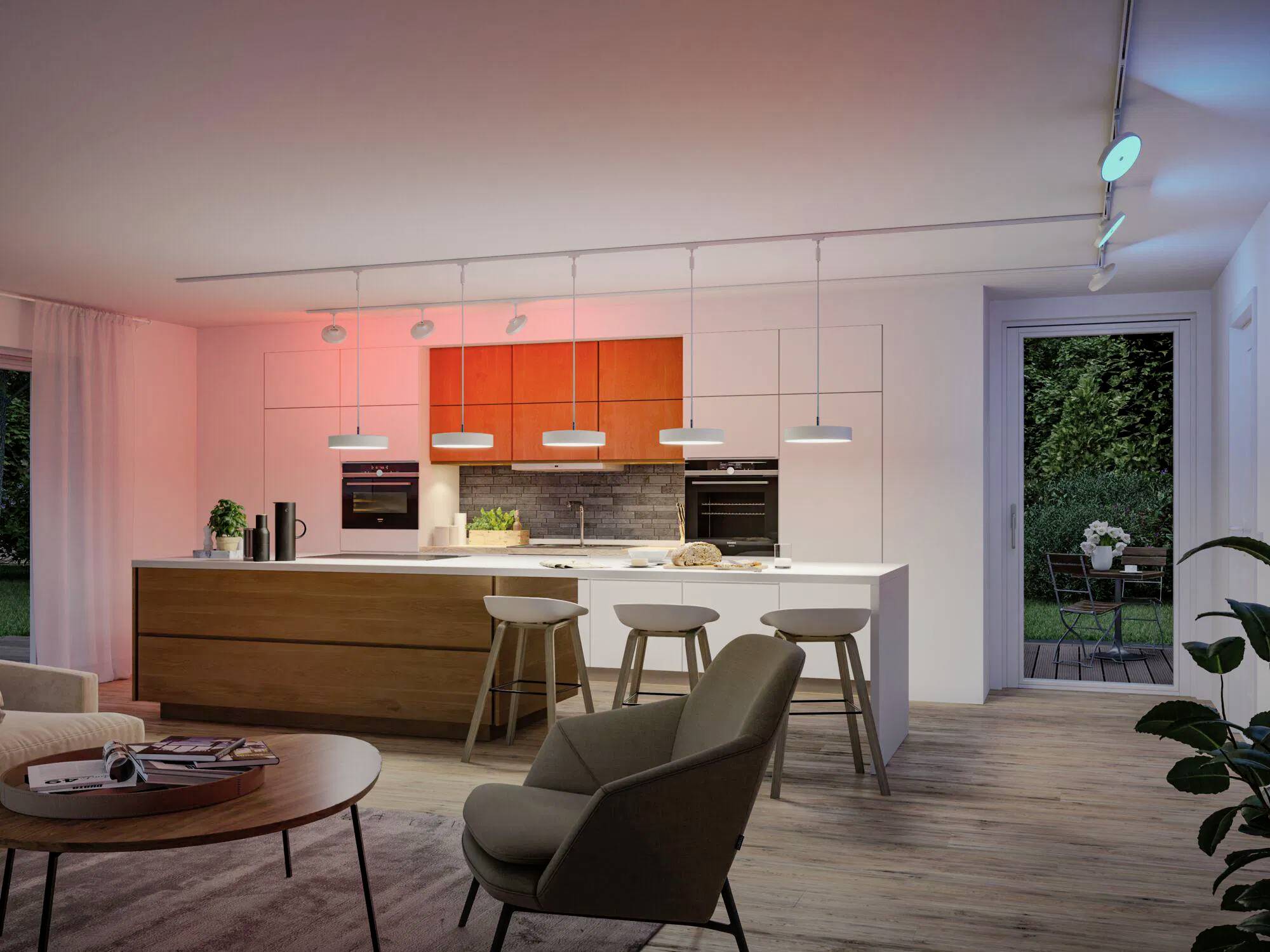 Moderne Küche mit Holzschränken, Barhocker und einer zentralen Kücheninsel. Stimmungsvolle Deckenbeleuchtung und Blick in den Garten durch Glastüren.