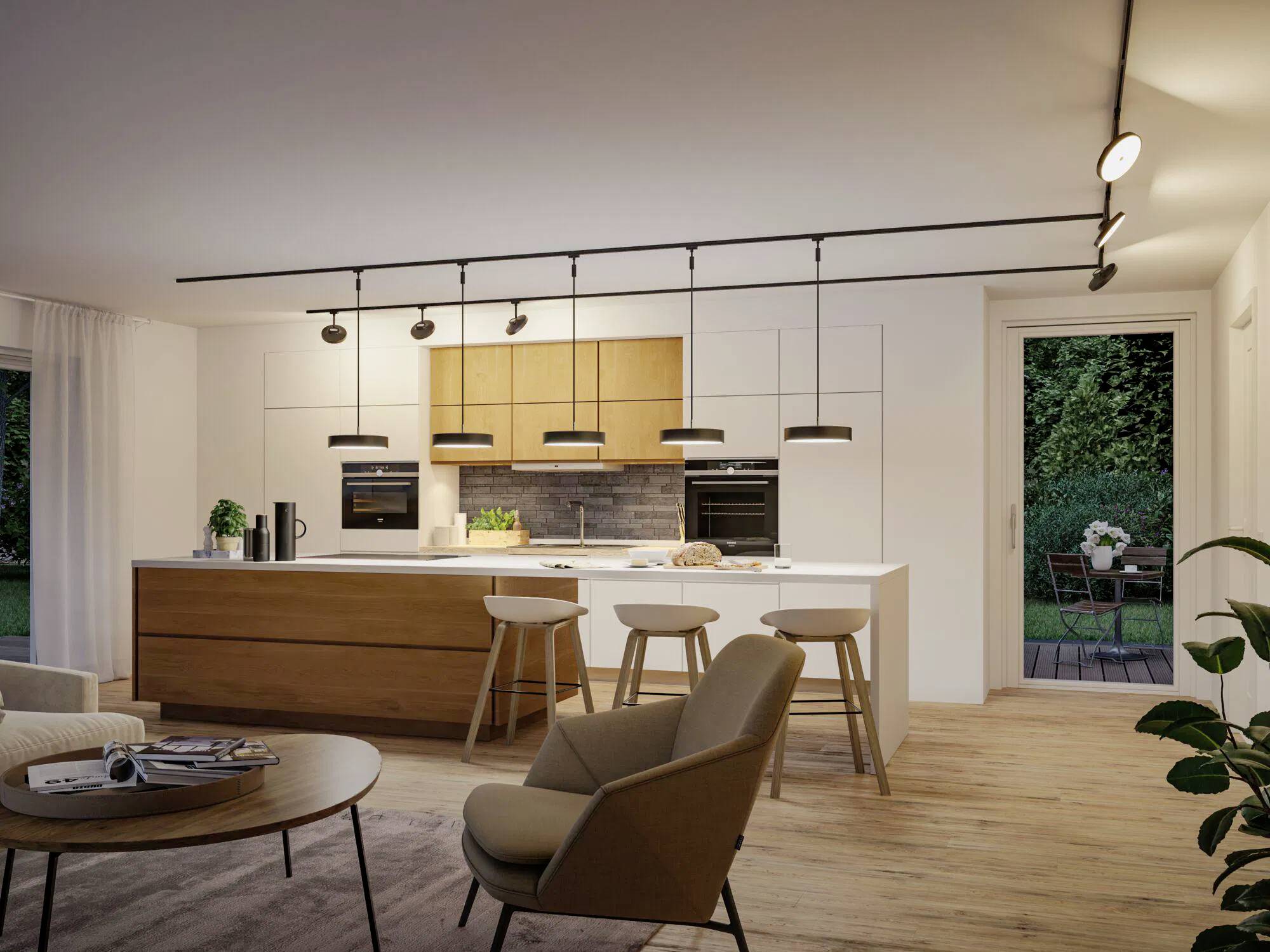 Eine moderne Küche und Wohnbereich mit Holzelementen, ausgestattet mit einer zentralen Kücheninsel mit Barhockern, Deckenleuchten und Blick in einen Garten.