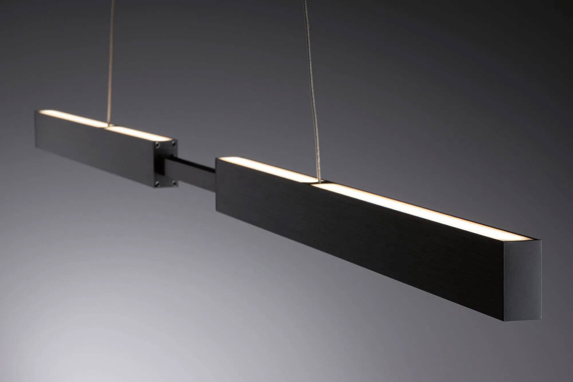 Eine moderne, rechteckige schwarze Pendelleuchte mit minimalistischem Design hängt vor einem dunklen Hintergrund.