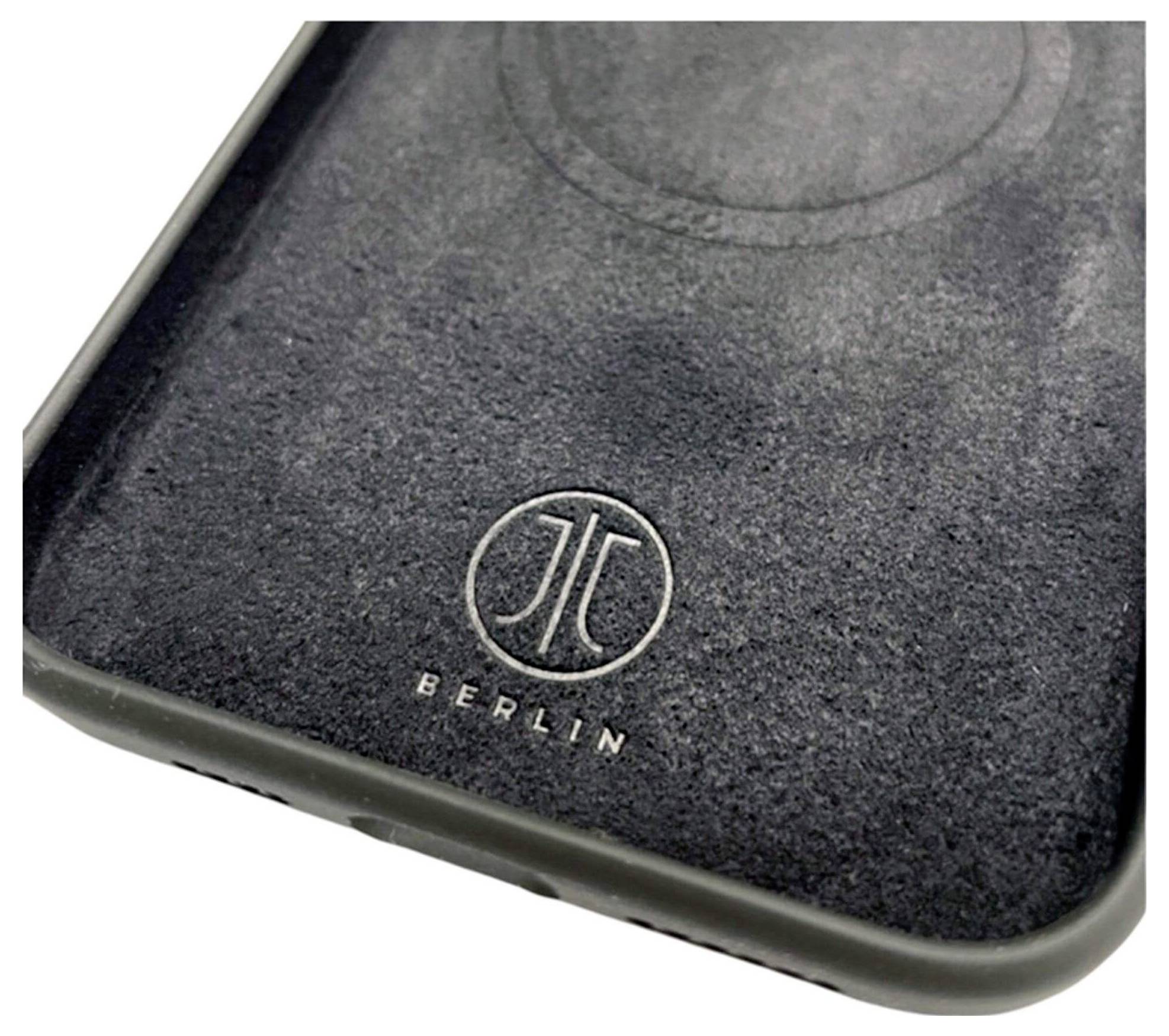 Eine Nahaufnahme einer dunklen, strukturierten Oberfläche mit einem kreisförmigen Design und dem geprägten Text ‚Berlin' unterhalb eines kreisförmigen Emblems.