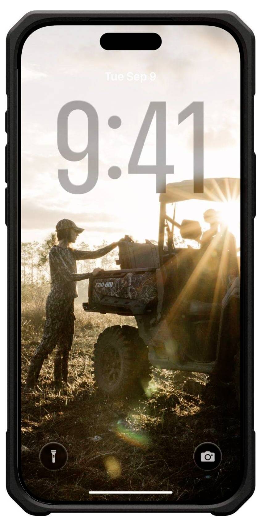 Eine Person in Outdoor-Ausrüstung und Kappe lädt Gegenstände auf einen ATV bei Sonnenuntergang. Sonnenlicht erzeugt Lens Flare. Die Telefonschnittstelle zeigt '9:41' und App-Symbole.