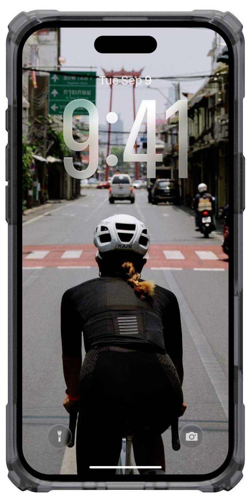 Ein Radfahrer mit Helm fährt auf einer leeren Straße mit Überkopfschildern. Eine Telefonoberfläche ist zu sehen, die die Uhrzeit '9:41' anzeigt.