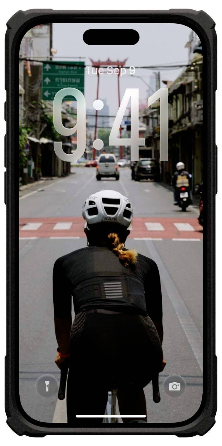 Ein Smartphone-Bildschirm zeigt einen Radfahrer auf einer Stadtstraße, der einen Helm und schwarze Kleidung trägt und sich einem Fußgängerüberweg nähert, während die Uhrzeit '9:41' angezeigt wird.