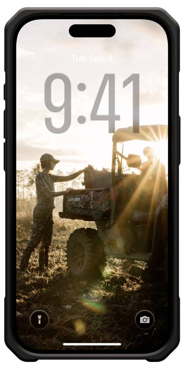 Eine Person steht bei Sonnenaufgang nahe einem Geländewagen auf einem Feld, mit Ausrüstung im Heck und Sonnenstrahlen, die durch die Landschaft scheinen.