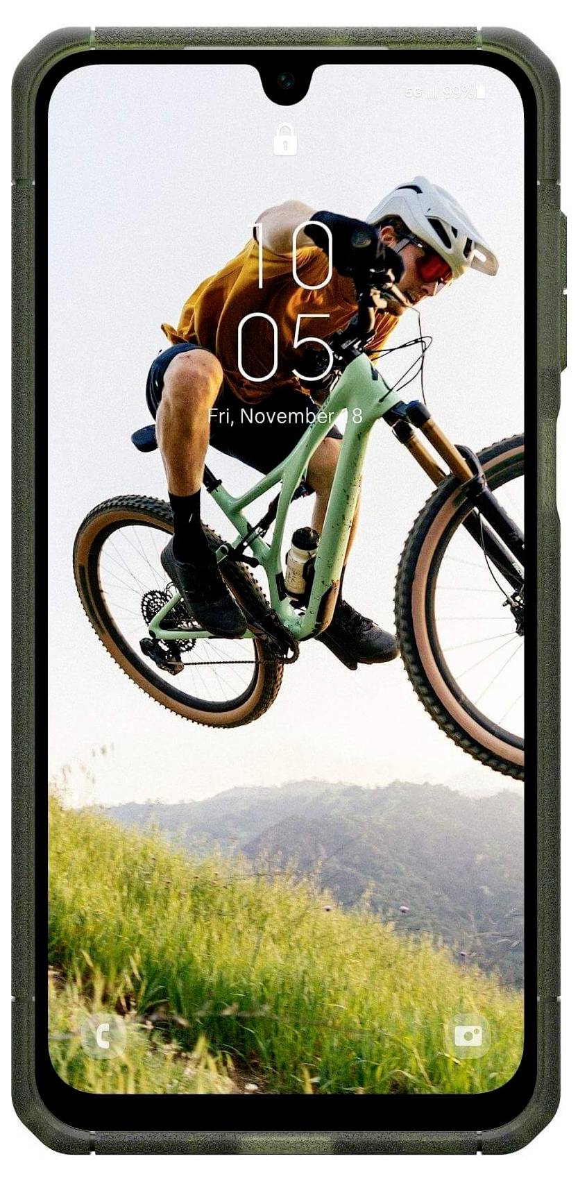Ein Mountainbiker in der Luft auf einem grasigen Hügel, mit Helm und Schutzausrüstung, mit einer Smartphone-Schnittstellen-Einblendung, die die Zeit und das Datum anzeigt.