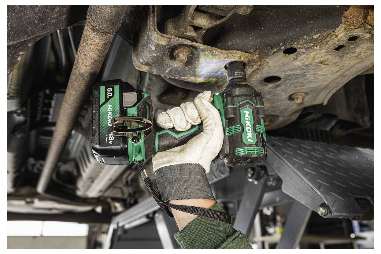 Person mit einer kabellosen Schlagschrauber bei Arbeiten an der Unterseite eines Fahrzeugs, wobei Autoreparatur oder Wartungsarbeiten im Mittelpunkt stehen.