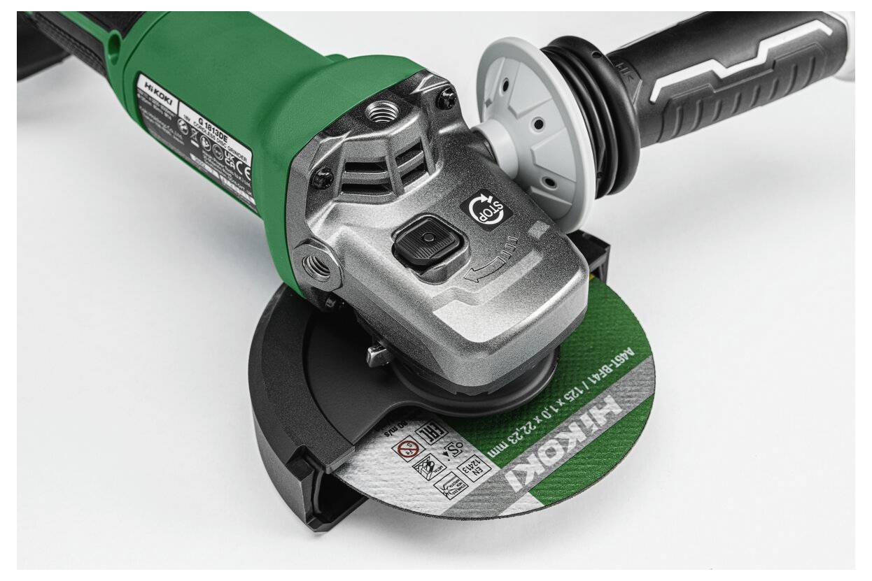 Eine Nahaufnahme einer Winkelschleifmaschine mit einer grünen Scheibe, die ein Metallschneidewerk zeigt. Details des Griffs und des Motorgehäuses sind deutlich sichtbar.