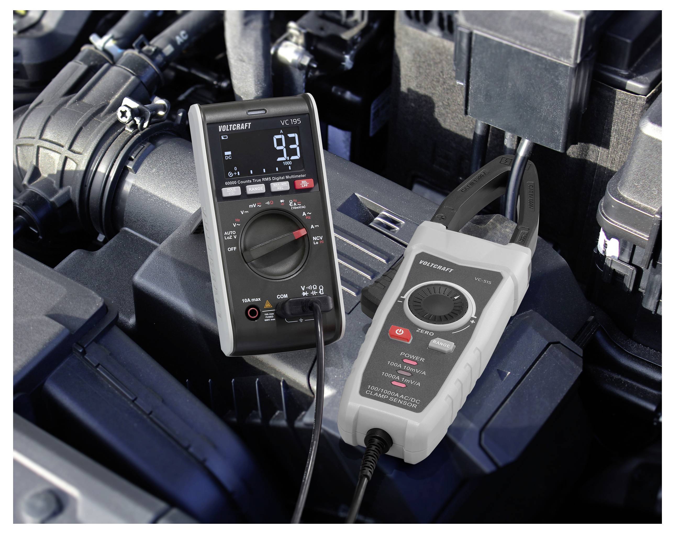 Ein Multimeter und ein Zangenmessgerät liegen auf einem Automotor und zeigen Messwerte an. Sie werden zur Messung elektrischer Parameter in Fahrzeugen verwendet.