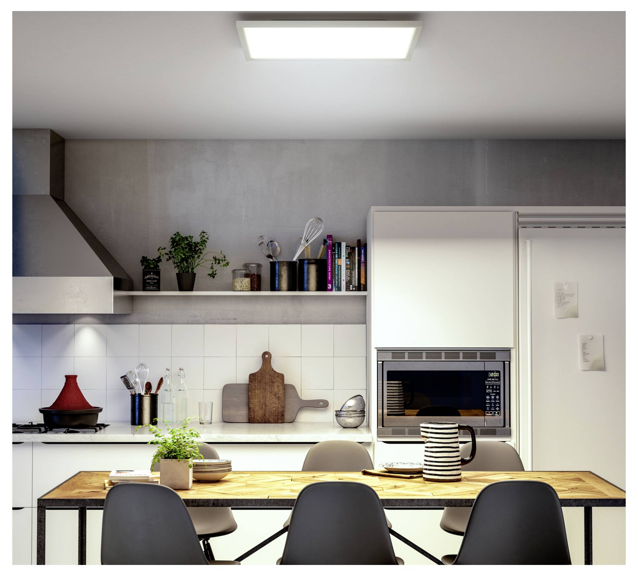 Eine moderne Küche mit einem Holztisch, der für das Essen gedeckt ist, Stühlen, Pflanzen und Kochutensilien auf Regalen. Ein Einbaubackofen und Bücher sind zu sehen.
