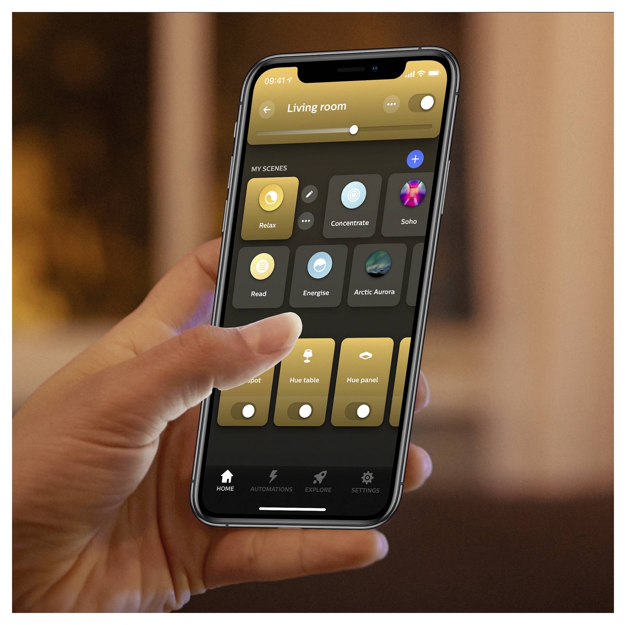 Person hält ein Smartphone mit einer Smart-Home-App-Oberfläche, die verschiedene Beleuchtungseinstellungen für das Wohnzimmer zeigt, wie zum Beispiel 'Entspannen' und 'Konzentrieren'.