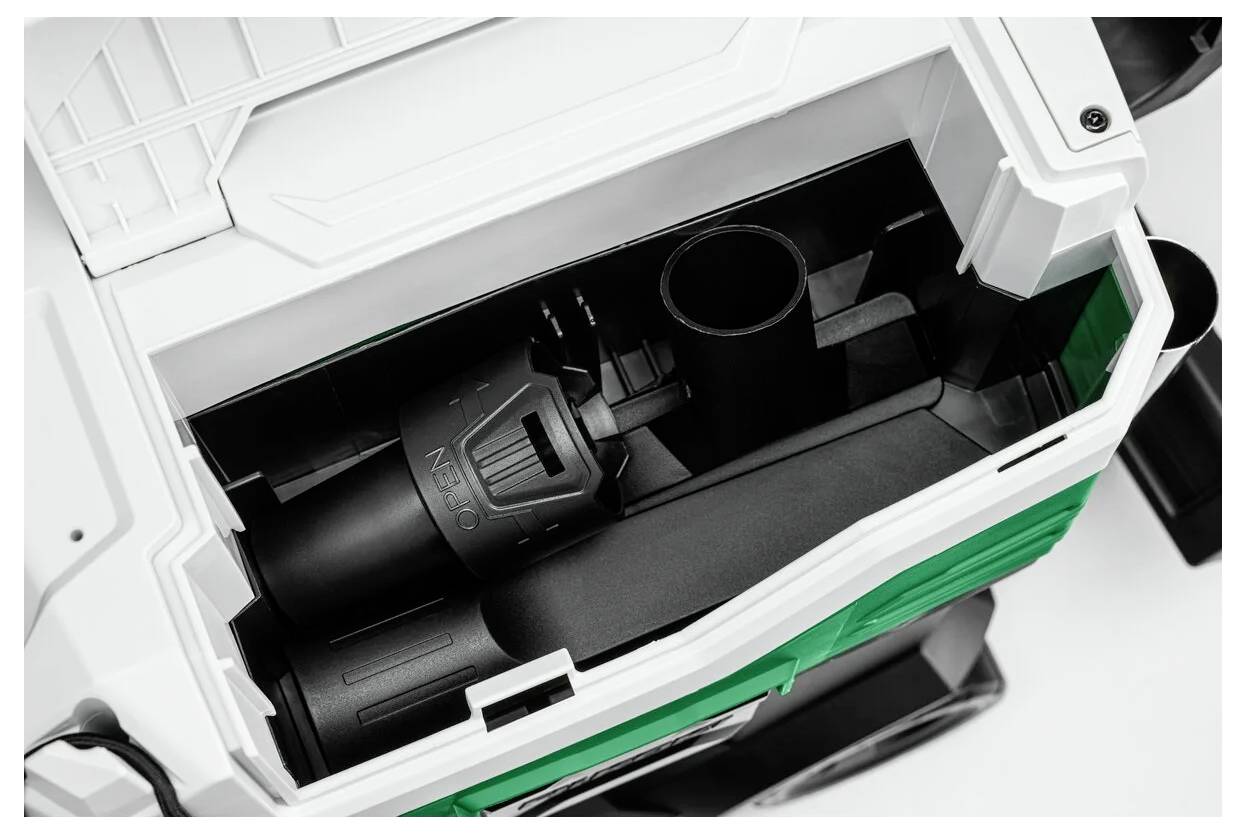 Draufsicht eines grün-weißen Maschinenabteils, das Innenkomponenten zeigt, darunter ein schwarzer zylindrischer Teil und eine hohle kreisförmige Öffnung.