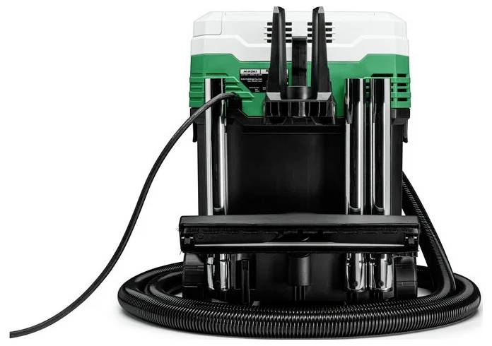 Ein Elektrowerkzeug mit einem grün-weißen Gehäuse, schwarzer Basis und angeschlossenem Schlauch. Es steht aufrecht und wird von hinten betrachtet.