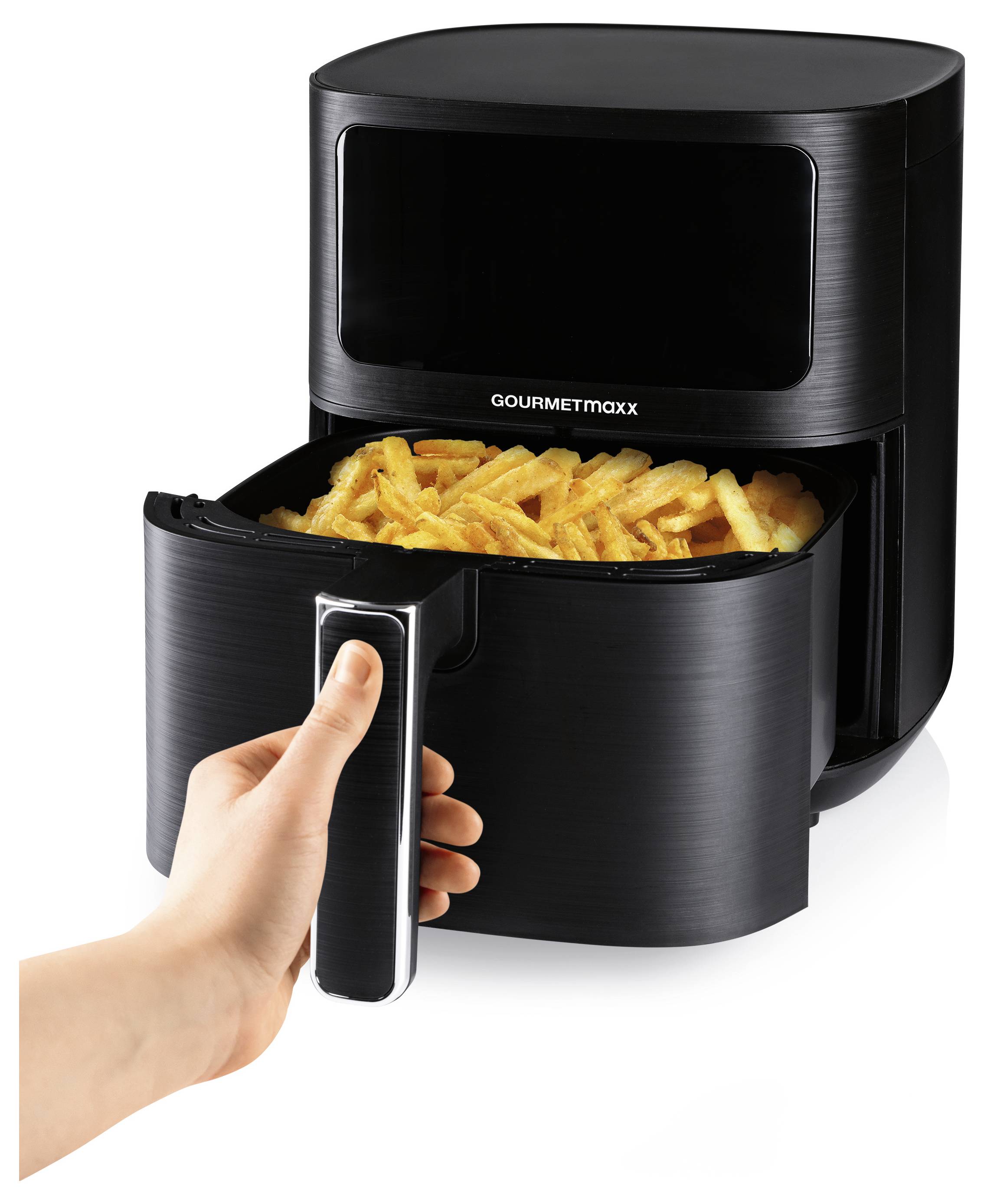 Eine Person holt ein Tablett mit gebackenen Pommes aus einem schwarzen Heißluftfryer.