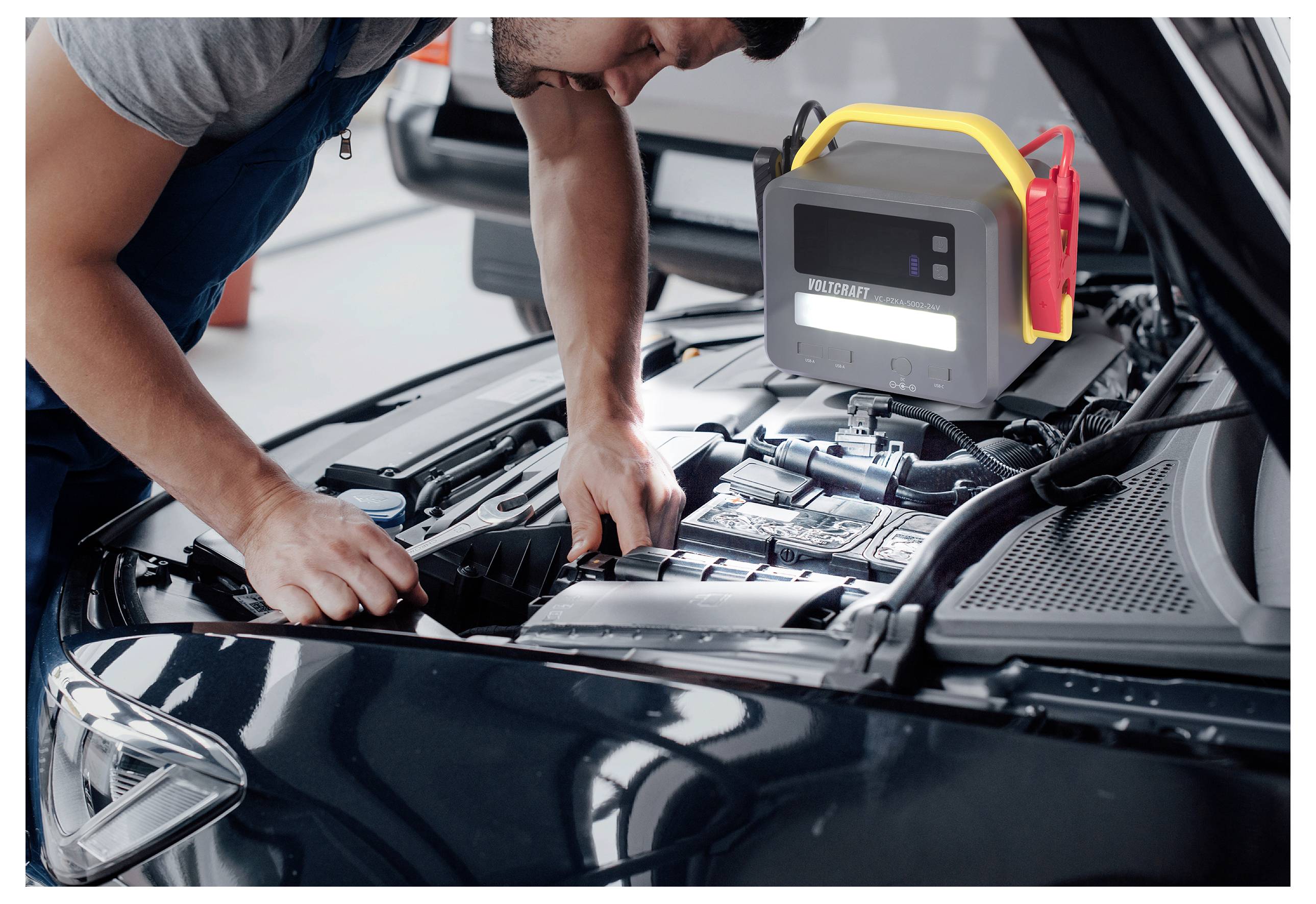 Ein Mechaniker arbeitet an einem Automotor mit einem Diagnosegerät, auf dem 