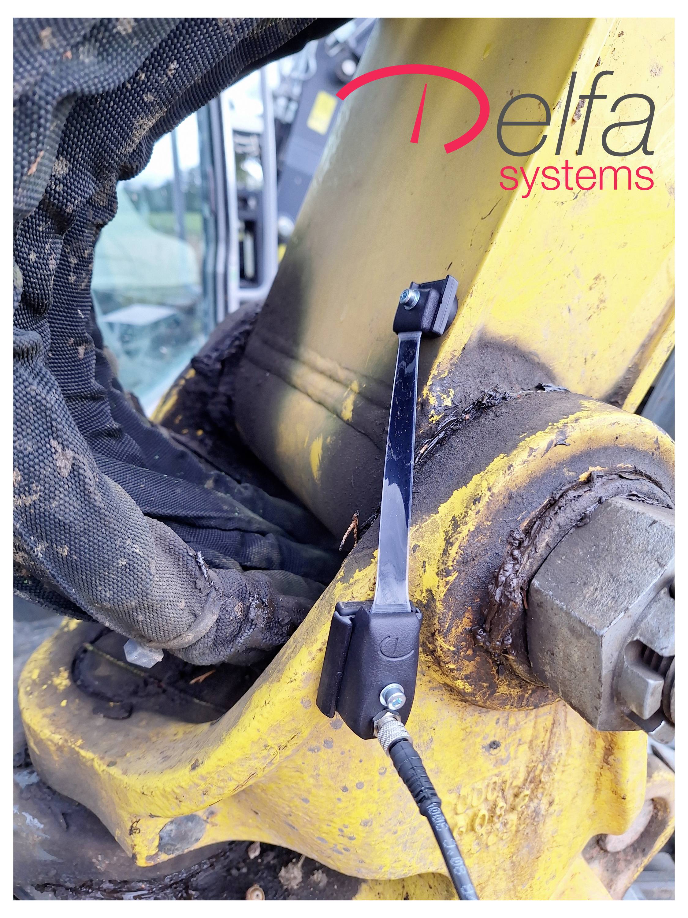 Eine schwarze mechanische Komponente ist an einem gelben Maschinenarm mit sichtbaren Kabeln befestigt. Das Logo "Delfa systems" befindet sich oben rechts.
