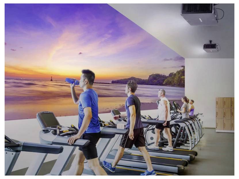 Menschen, die in einem Fitnessstudio auf Laufbändern trainieren und einer großen Wandmalerei mit einem friedvollen Strand-Sonnenuntergang gegenüberstehen.