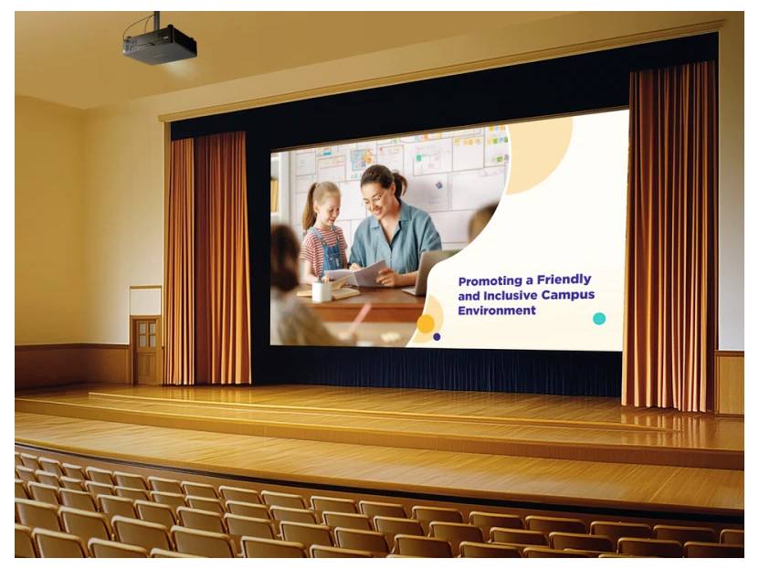 Ein Auditorium zeigt eine große Leinwand mit einer Folie mit dem Titel ‚Förderung eines freundlichen und inklusiven Campusumfelds' mit einem Bild von einer Lehrkraft und einem Kind.