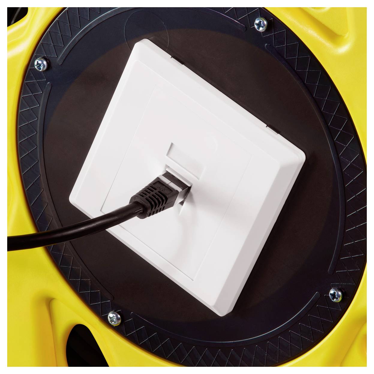 Ein schwarzes Kabel ist in eine weiße Steckdose an einer gelben und schwarzen industriellen Oberfläche eingesteckt, was einen Stromverbindungsaufbau andeutet.