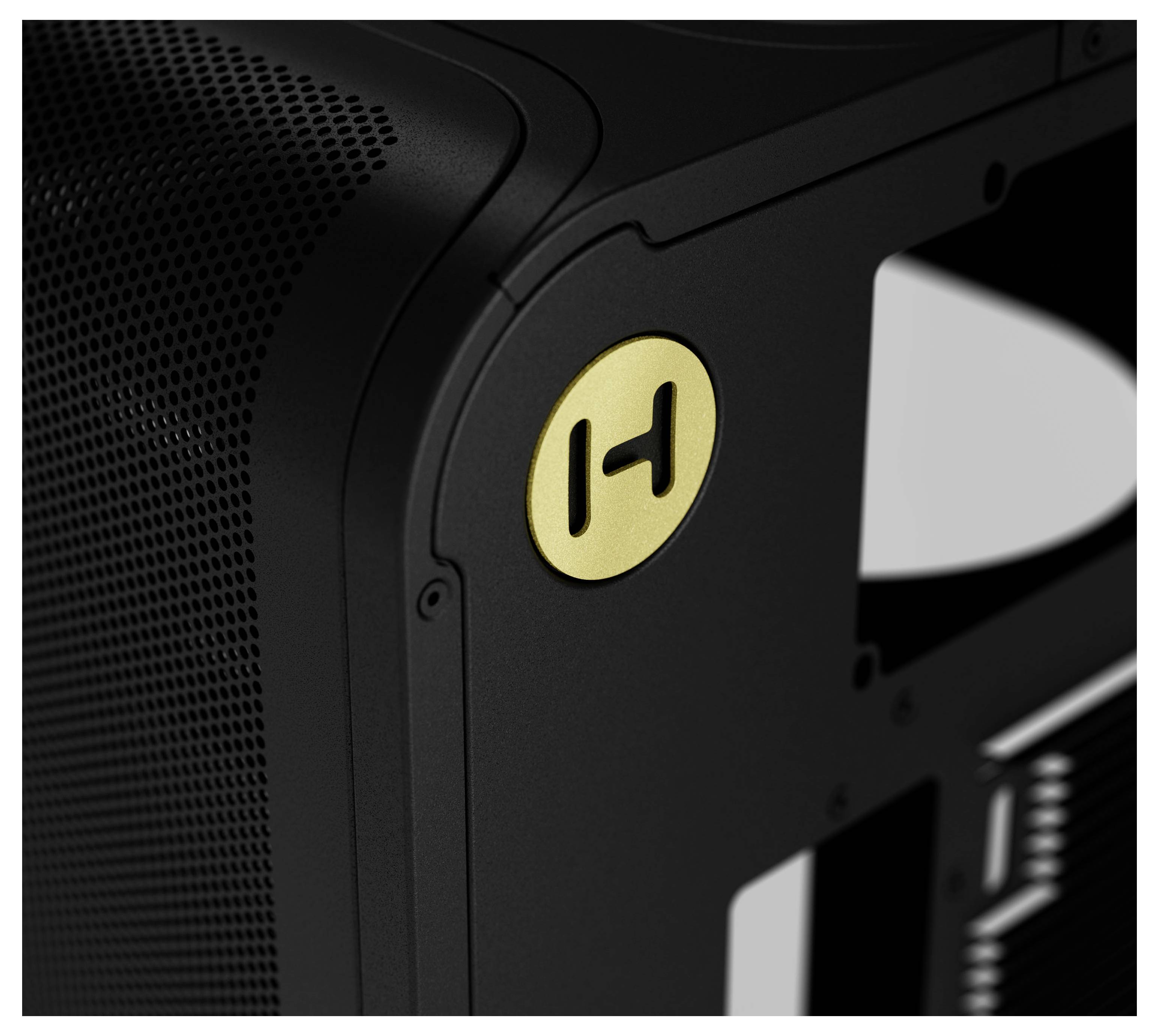 Eine Nahaufnahme eines schlanken schwarzen Geräts mit detailliertem Maschenmuster und einem kreisförmigen goldenen Emblem mit einem stilisierten 'H'.
