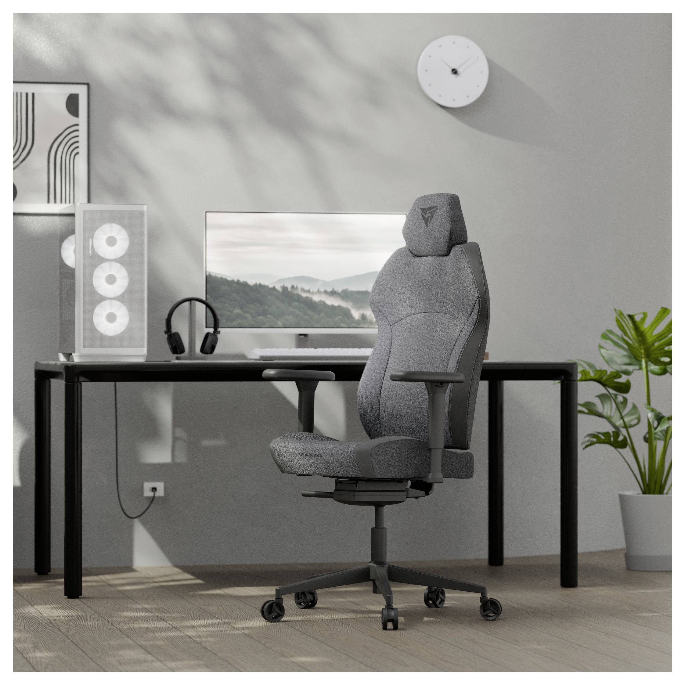 Ein modernes Homeoffice mit einem grauen ergonomischen Stuhl, einem schwarzen Schreibtisch, einem großen Monitor, einer Topfpflanze, einer Wanduhr und minimaler Dekoration.