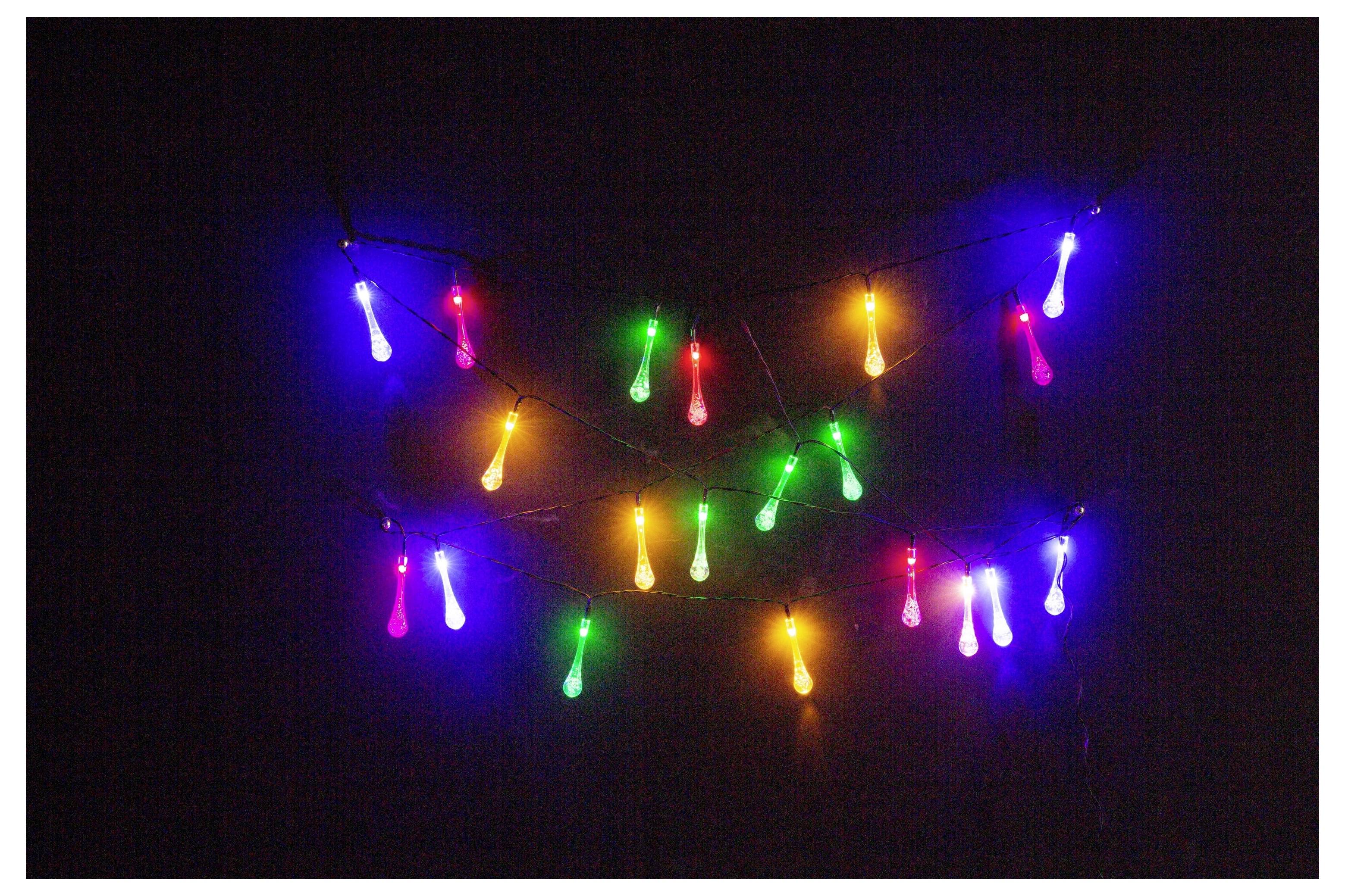 Bunte Lichterketten hängen vor einem dunklen Hintergrund, mit Glühbirnen in rot, grün, blau, rosa und gelben Farbtönen.