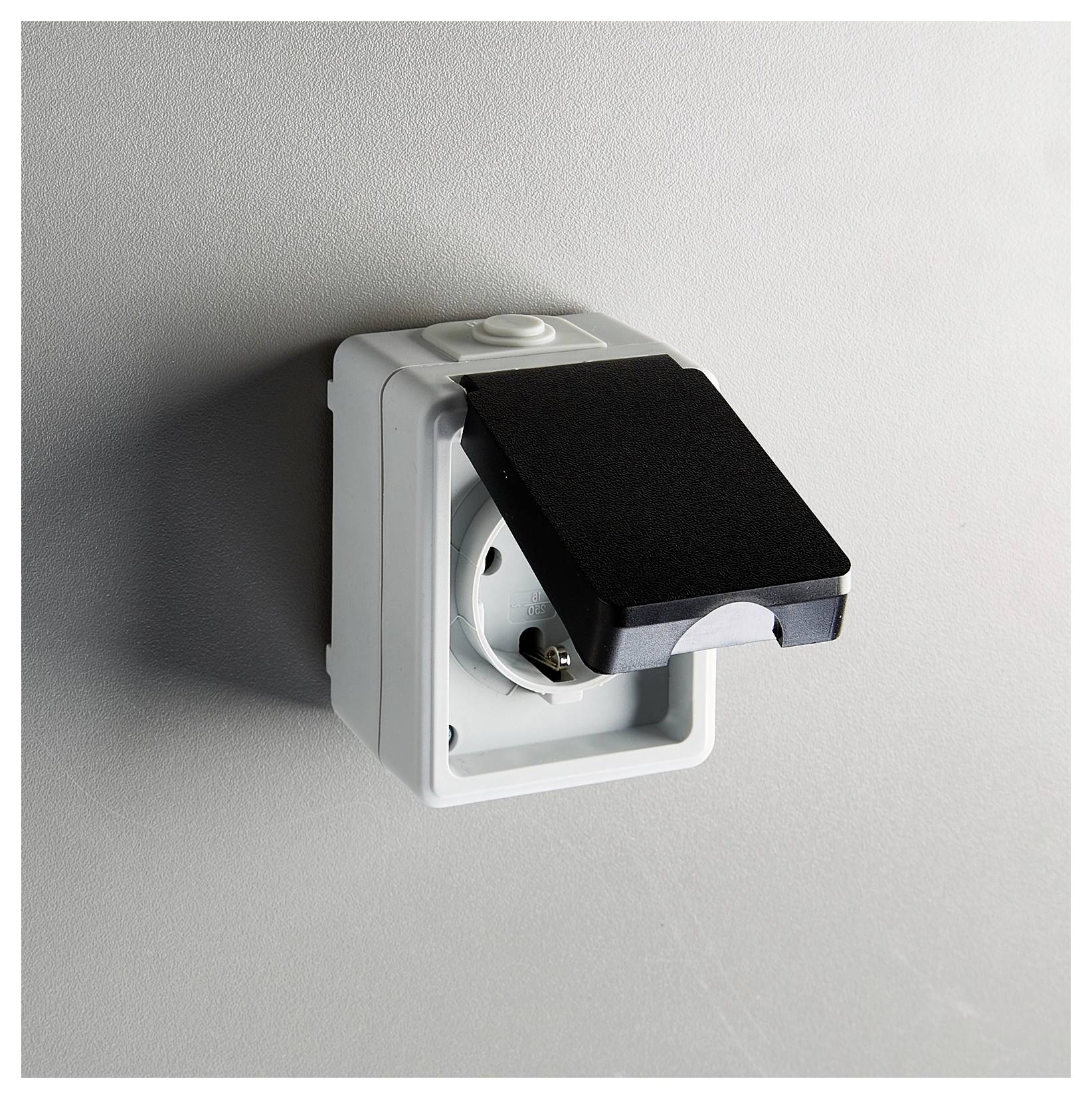 Eine wandmontierte elektrische Steckdose mit einem geschlossenen Schutzdeckel, die für Sicherheit und Wetterfestigkeit konzipiert ist.