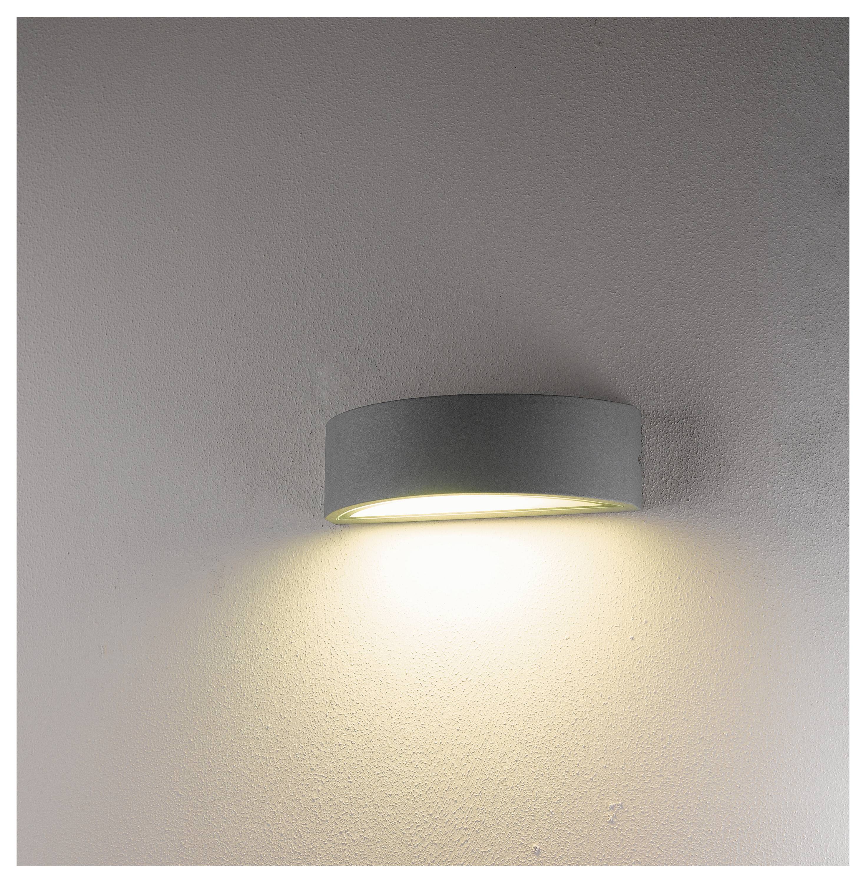 Eine moderne, runde Wandleuchte mit einem grauen Schirm strahlt weiches, warmes Licht aus und beleuchtet die Wand darunter.