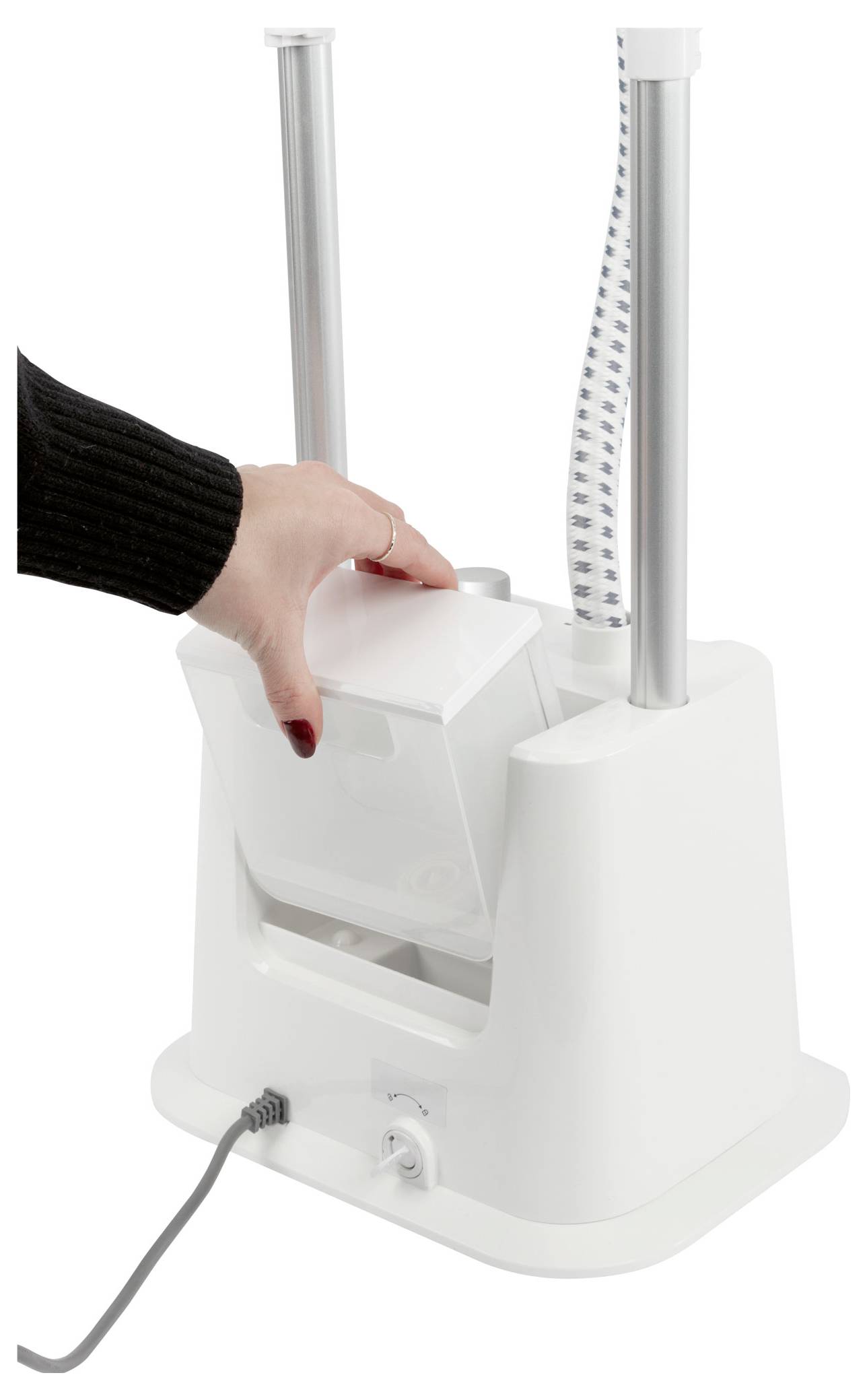 Eine Person legt einen Gegenstand in eine weiße Maschine mit Metallstäben und einem Netzkabel. Die Maschine scheint dafür ausgelegt zu sein, Gegenstände zu halten oder zu verarbeiten.