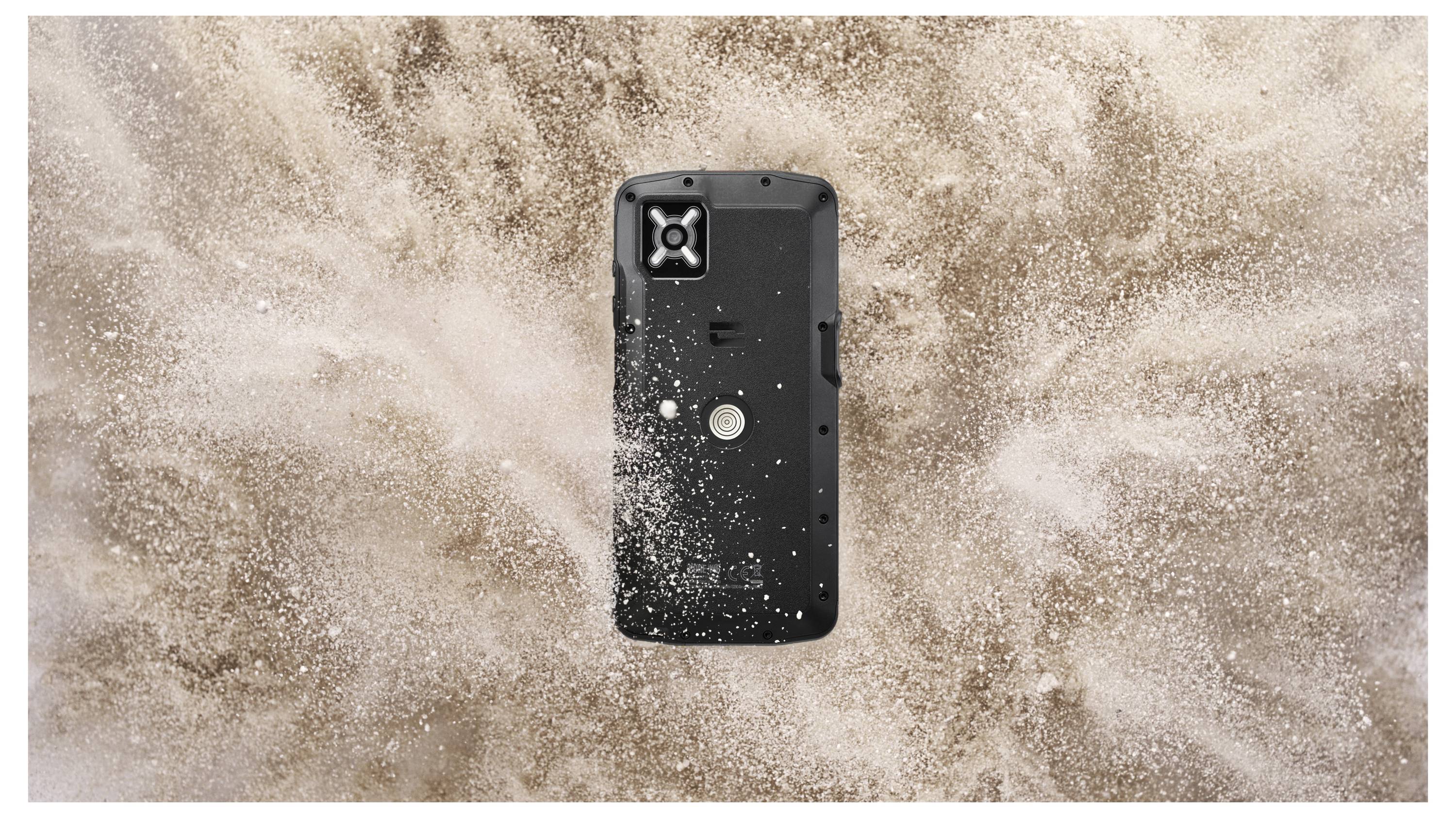 Ein robustes Smartphone, umgeben von einer Wolke aus Sand, das seine Widerstandsfähigkeit und Belastbarkeit in rauen Umgebungen unter Beweis stellt.