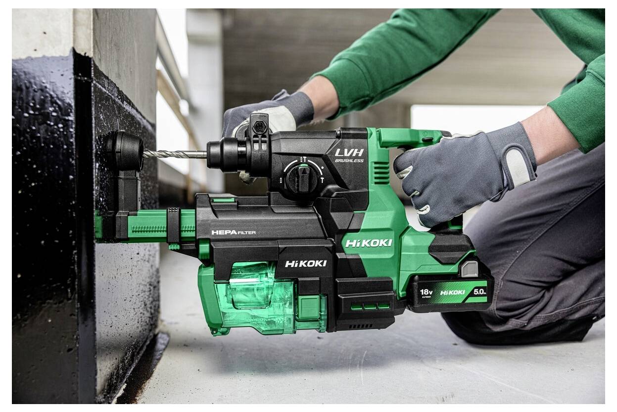 Eine Person, die eine grün-schwarze Bohrmaschine der Marke ‚HiKOKI' verwendet, um in eine Metalloberfläche zu bohren, während sie Handschuhe trägt.