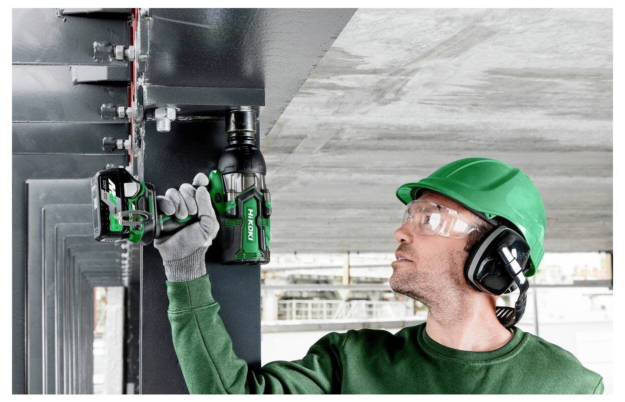 Ein Arbeiter mit Schutzausrüstung verwendet ein Elektrowerkzeug, um Bolzen an einem Stahlträger zu befestigen, was auf Bau- oder Instandhaltungsarbeiten hindeutet.