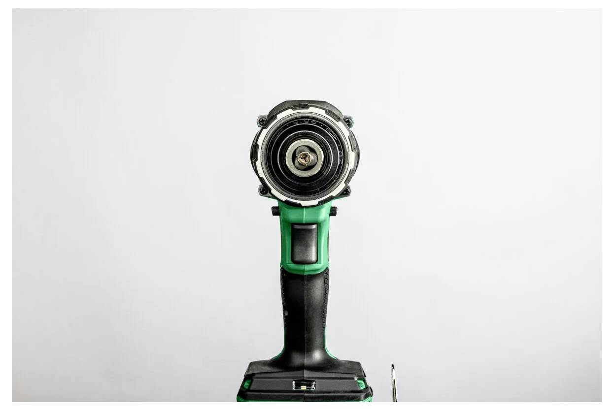 Eine grüne und schwarze kabellose Akku-Bohrmaschine, von vorne gesehen, mit sichtbarem Bohrfutter und Auslöser, vor einem einfarbigen weißen Hintergrund.