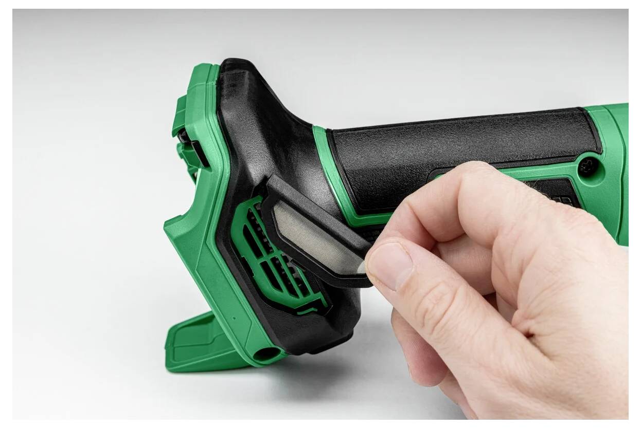 Eine Hand öffnet das Batteriefach eines tragbaren Elektrowerkzeugs. Das Werkzeug ist grün und schwarz mit einem strukturierten Griff für besseren Halt.