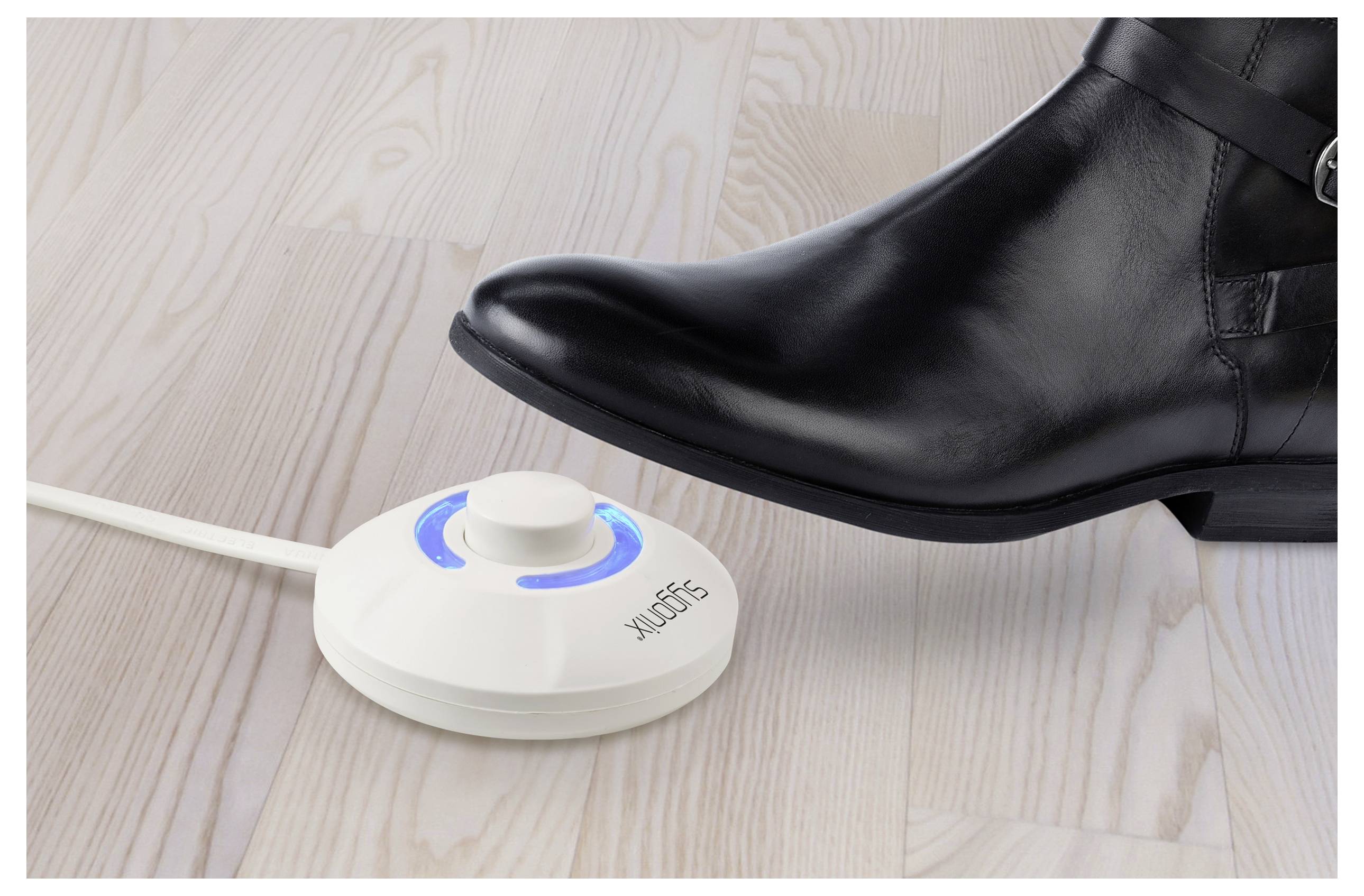 Ein Fuß in einem schwarzen Schuh drückt einen runden, weißen Fußschalter mit blauen Lichtern auf einem Holzboden. Der Schalter ist mit 