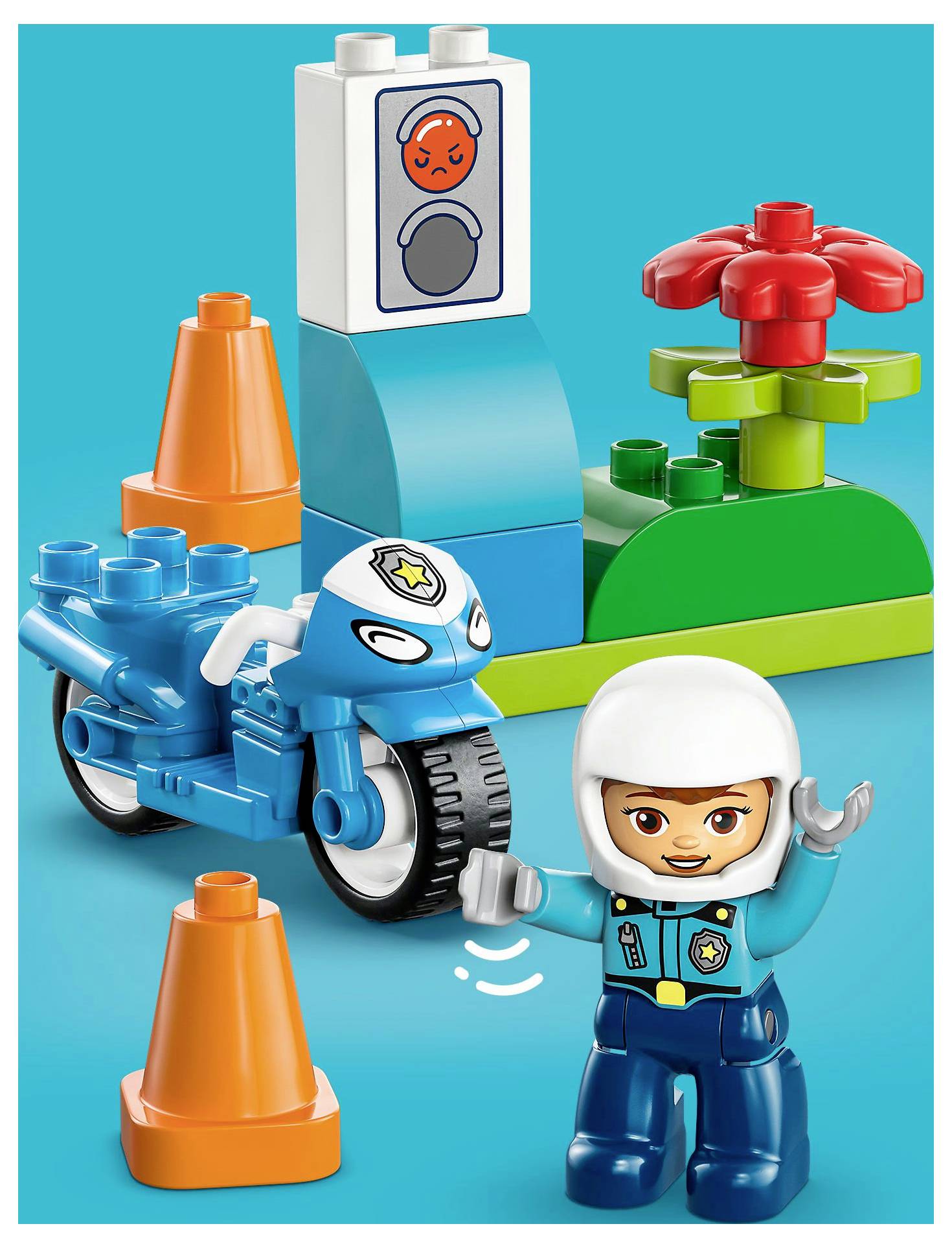 Eine Spielfigur in Polizeiuniform winkt in der Nähe eines blauen Spielzeugs-Motorrads, orangefarbener Verkehrskegel und einer Ampel mit rotem Signal.