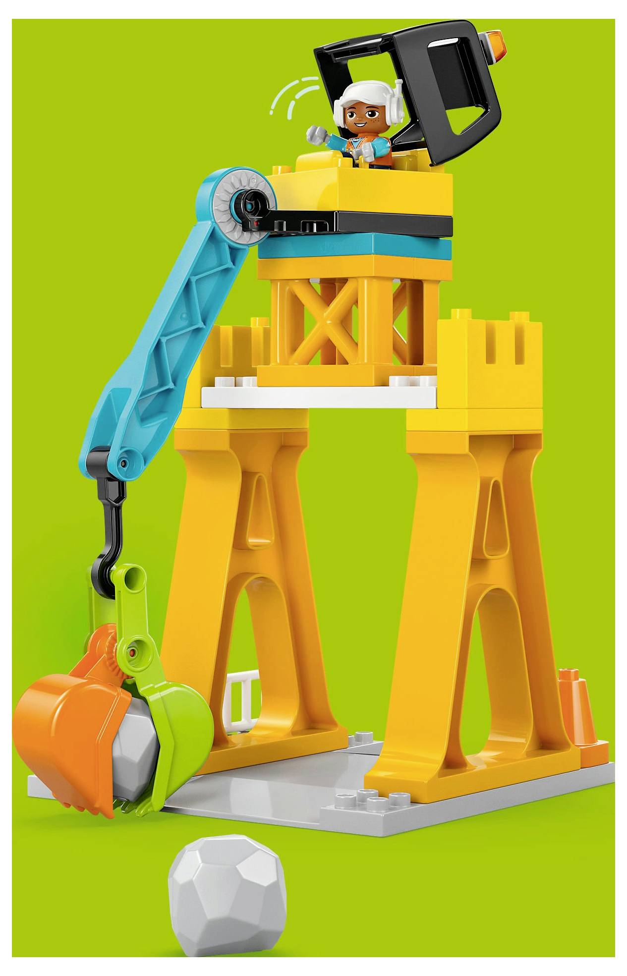 Ein bunter Spielzeugkran aus orangen, blauen und grünen Teilen mit einer Figur, die ihn bedient, vor einem grünen Hintergrund.