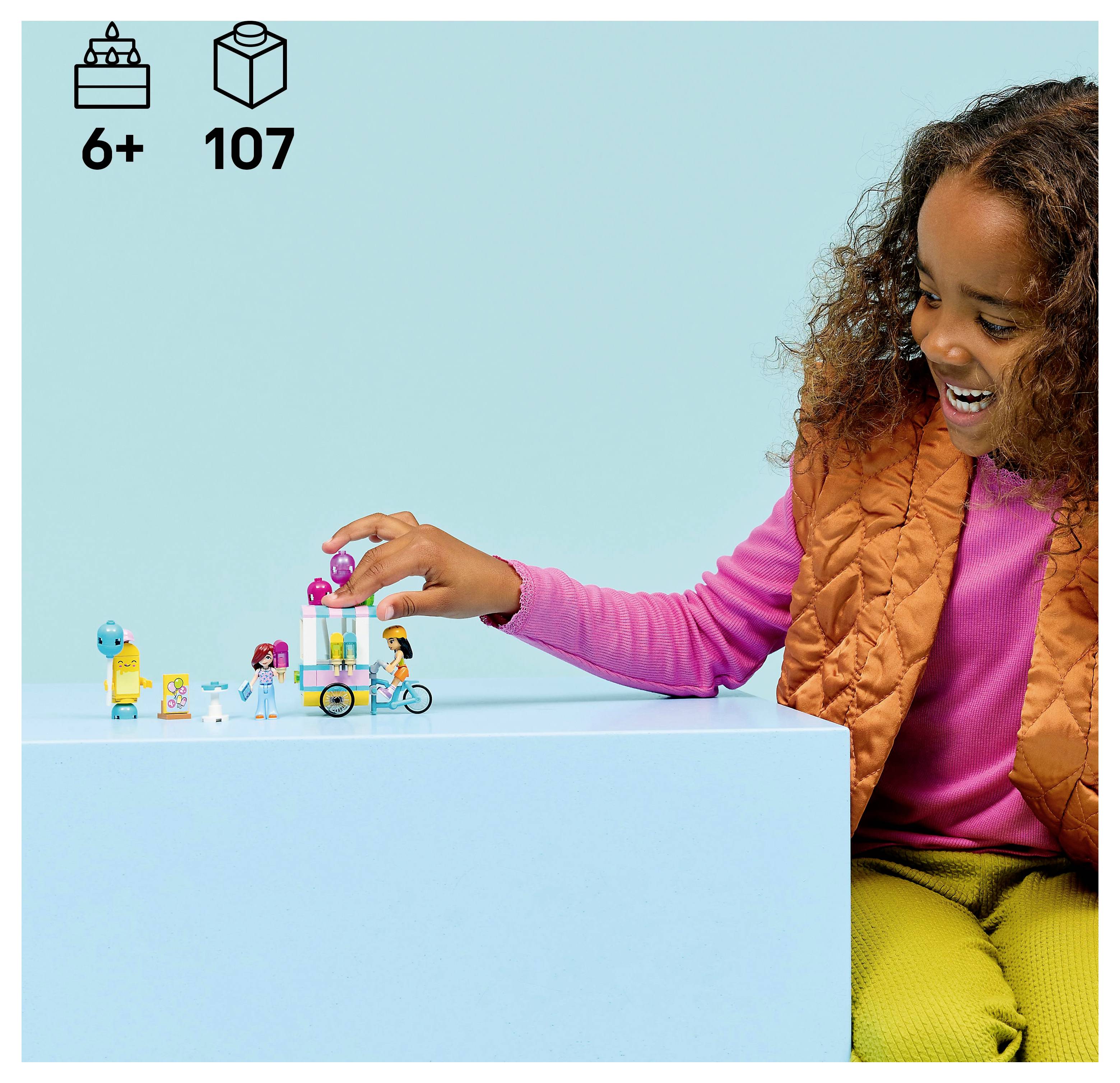 Kind, das mit Spielfiguren und einem Fahrrad-Set auf einer hellblauen Oberfläche spielt. Alter 6+, 107 Teile in den Symbolen oben links angegeben.